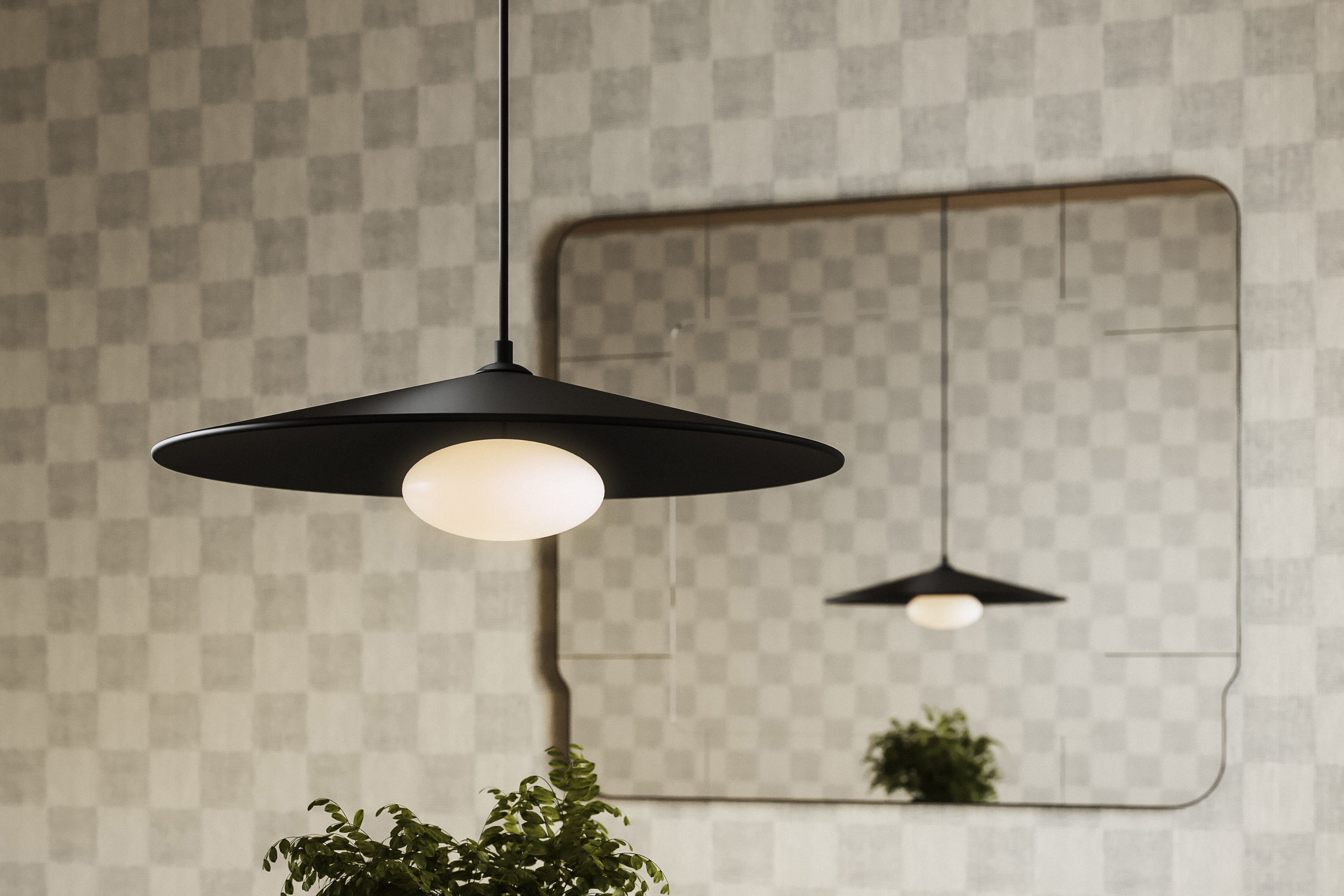 Modern black metal LED pendant light with a wide disc shade and white globe diffuser, reflected in a wall mirror against a subtle checkered backdrop.