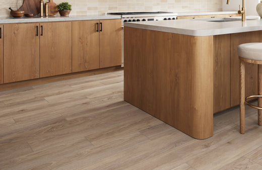 Light wood look porcelain tile kitchen floor in a modern interior with natural grain variation, warm wood cabinetry, white countertops, and a minimalist island layout.