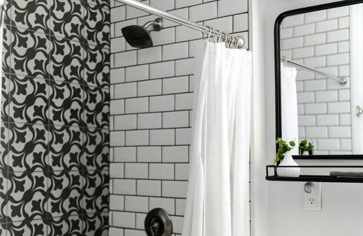 Black and white bathroom shower with white subway tiles and black grout lines, paired with patterned black tile accent wall and chrome fixtures.
