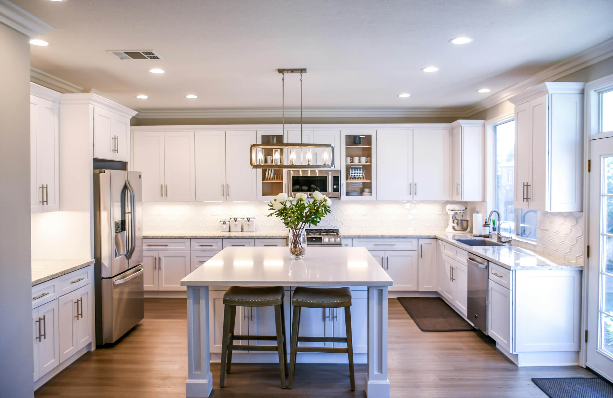 Open concept kitchen with dining and living areas connected, featuring a large island, warm wood floors, and ample natural light.