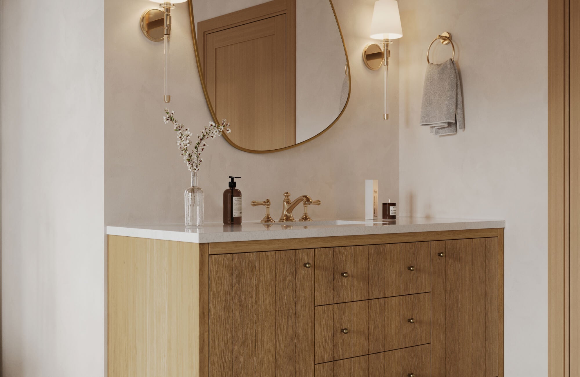 Warm, minimalist bathroom scene featuring a refined 60 inch vanity with natural wood cabinetry, a smooth white stone countertop, and classic brass fixtures, accented by an oval mirror, soft wall sconces, and subtle decorative details.