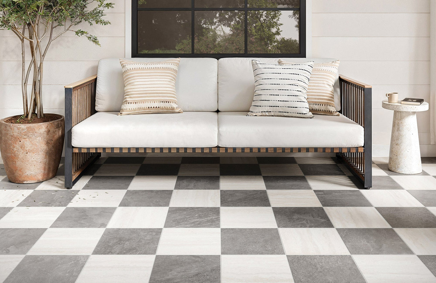Outdoor patio with checkerboard tile in grey and white, paired with modern wood seating.