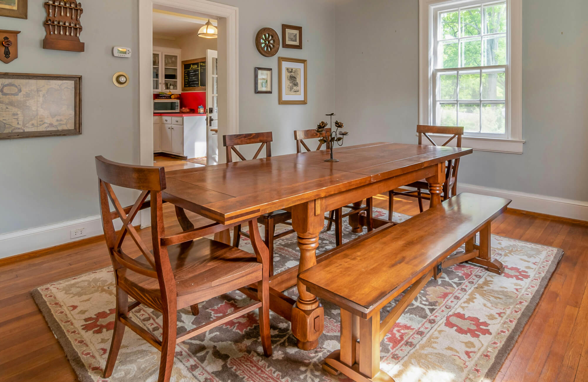 Wooden dining bench paired with a matching table and chairs, creating shared seating in a traditional dining room setting.