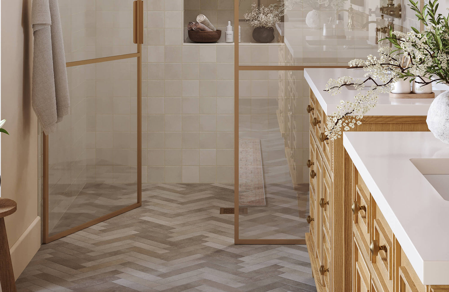Elegant bathroom with herringbone tile flooring, soft cream shower tiles, and warm oak cabinetry with brass hardware.