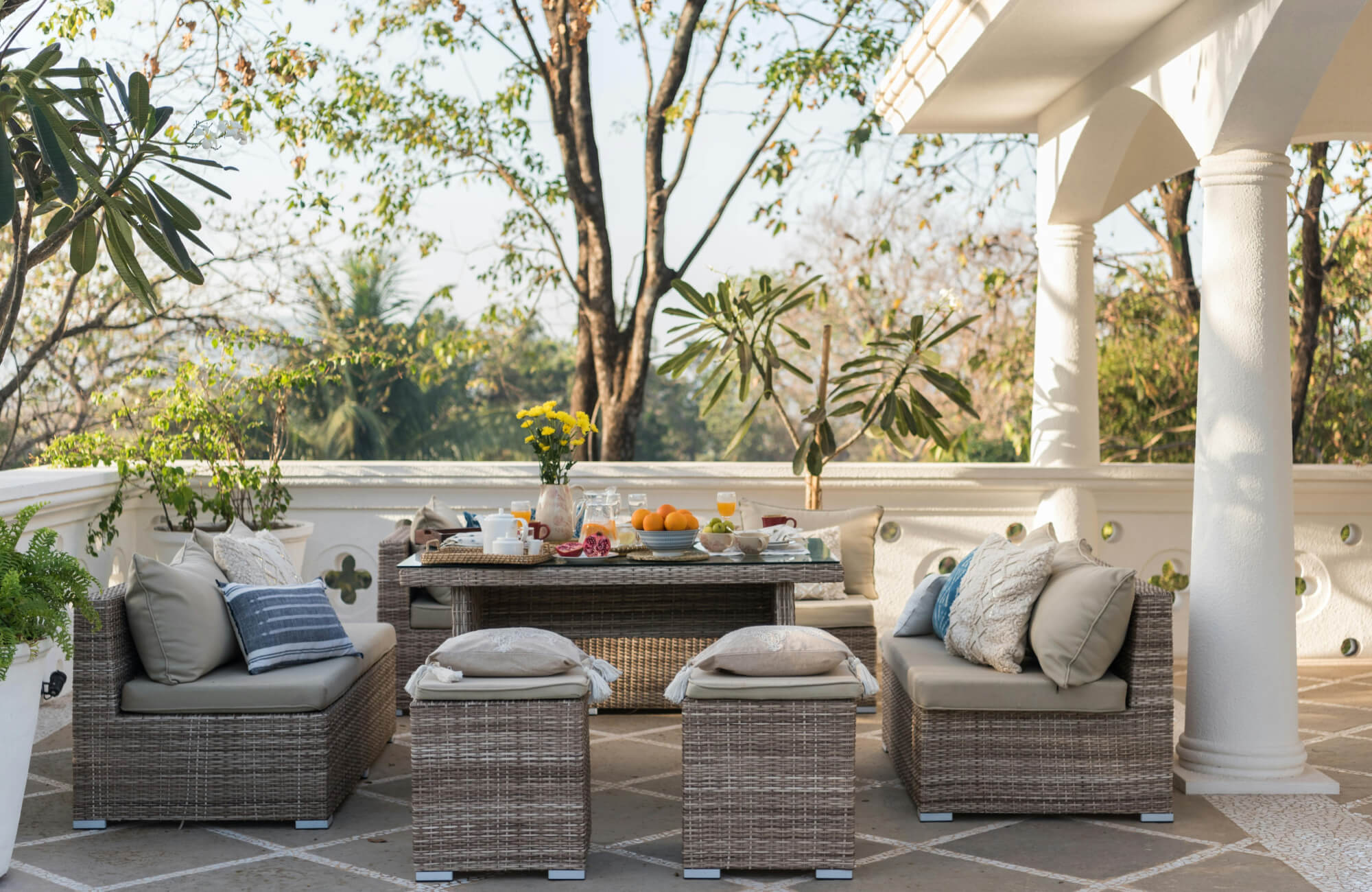 Light-toned patio tiles define a covered outdoor seating area, creating a clean, structured surface beneath woven furniture.