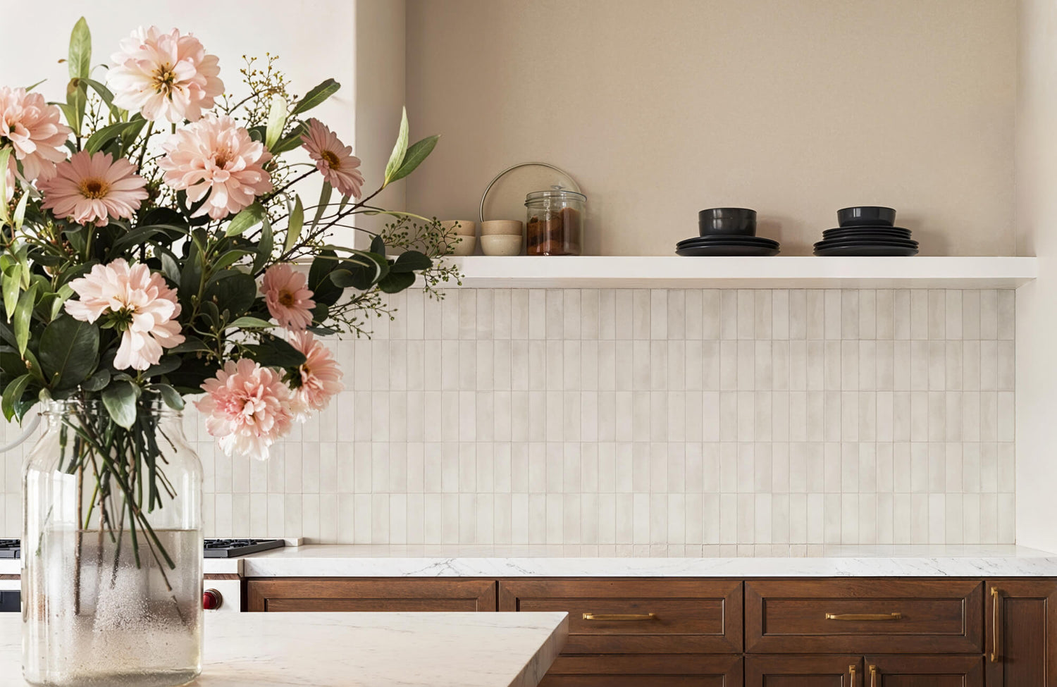 A warm, modern kitchen with a marble countertop and wood cabinetry, featuring a vertically stacked neutral subway tile backsplash that demonstrates how classic tiles can feel updated and on-trend.