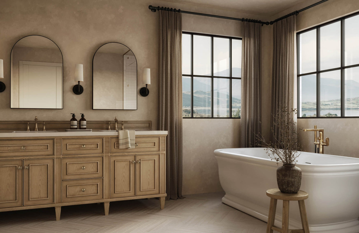 Soft-toned bathroom featuring a dual-sink wood vanity, brass fixtures, and a classic soaking tub beside large windows with scenic landscape views.