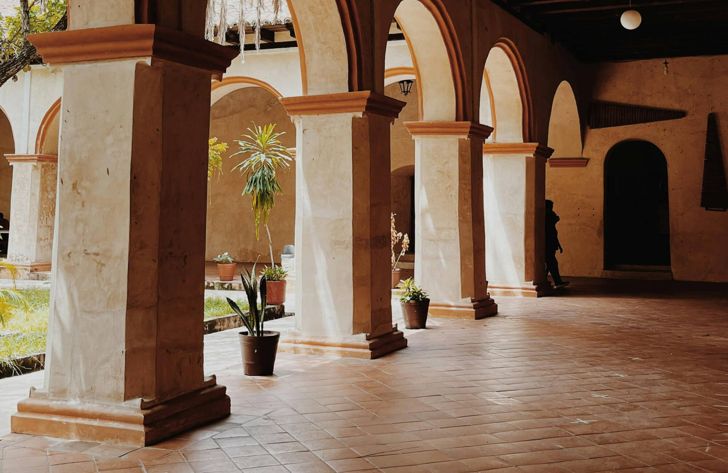 Outdoor corridor with terracotta floor tiles in a diagonal layout, enhancing rustic architecture and archway design.