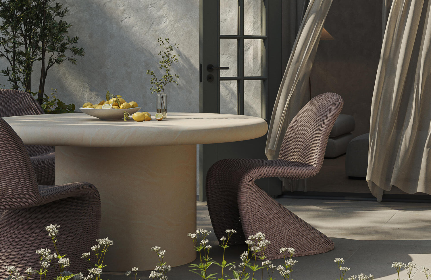 Round pedestal outdoor coffee table with textured concrete finish on a modern patio dining space with woven chairs.