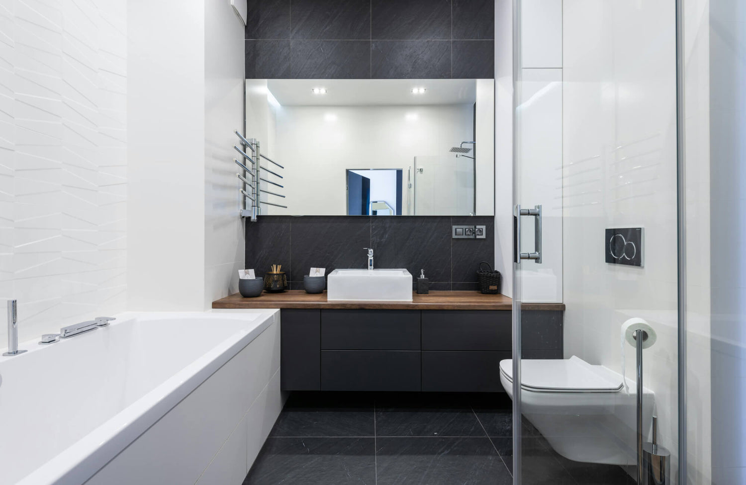 Modern bathroom with a black vanity, white sink, and large mirror, creating an open, spacious look with clean contrast.