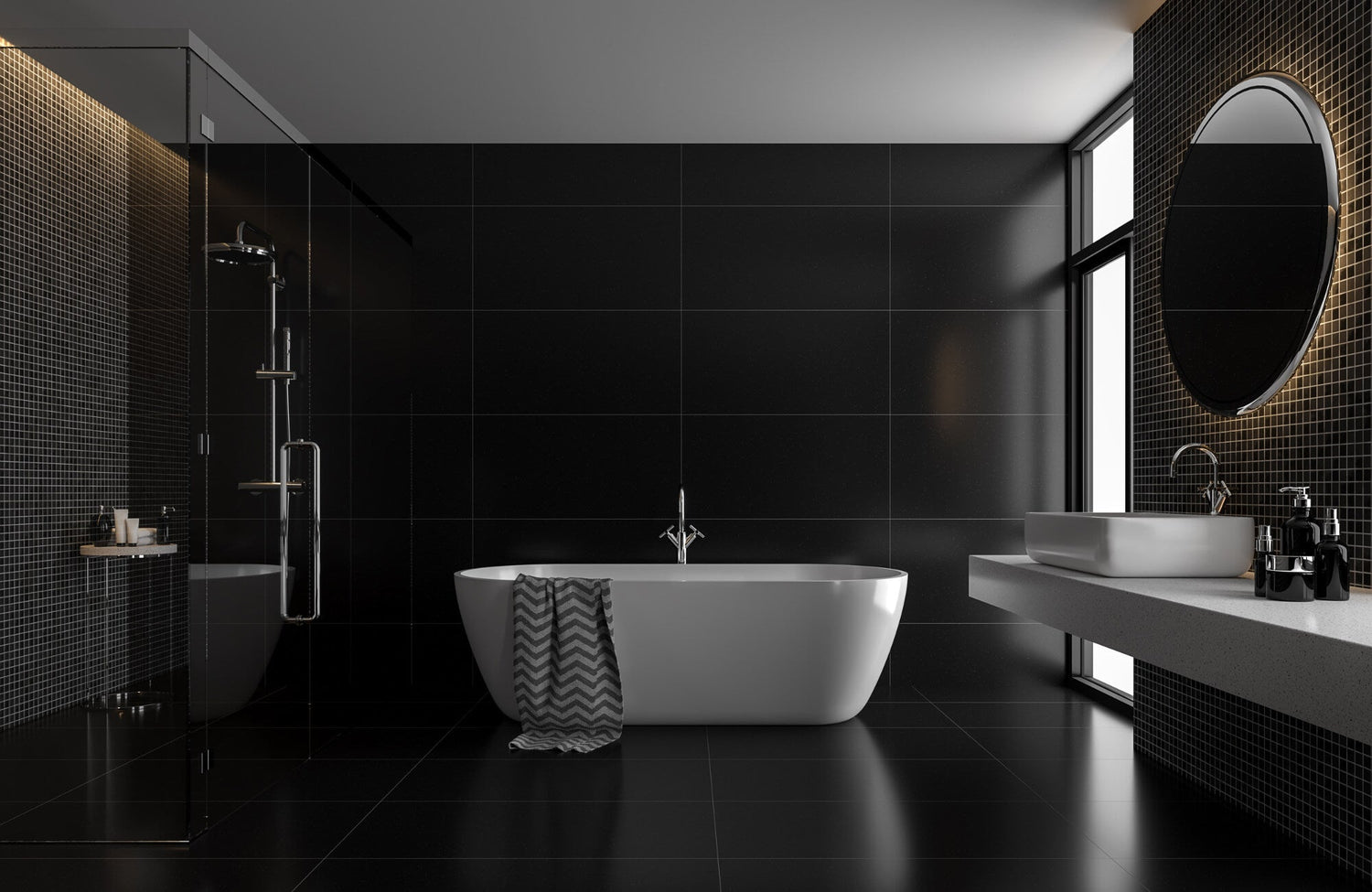 Modern bathroom with black wall and floor tiles, a freestanding white tub, floating vanity, and backlit round mirror near a window.