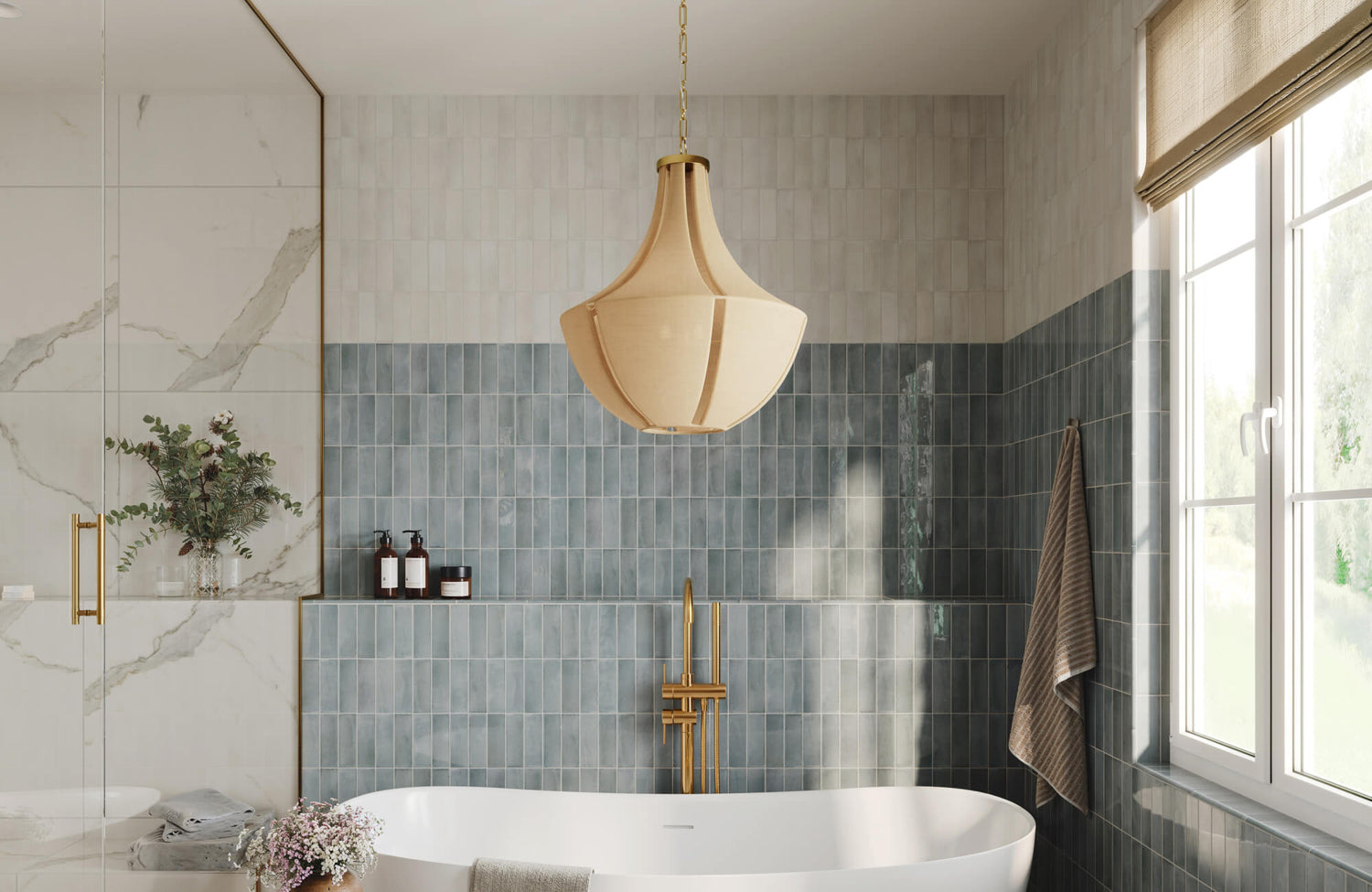 Serene bathroom with a two-tone vertical tile wall, freestanding tub, brass fixtures, and a sculptural beige pendant light.
