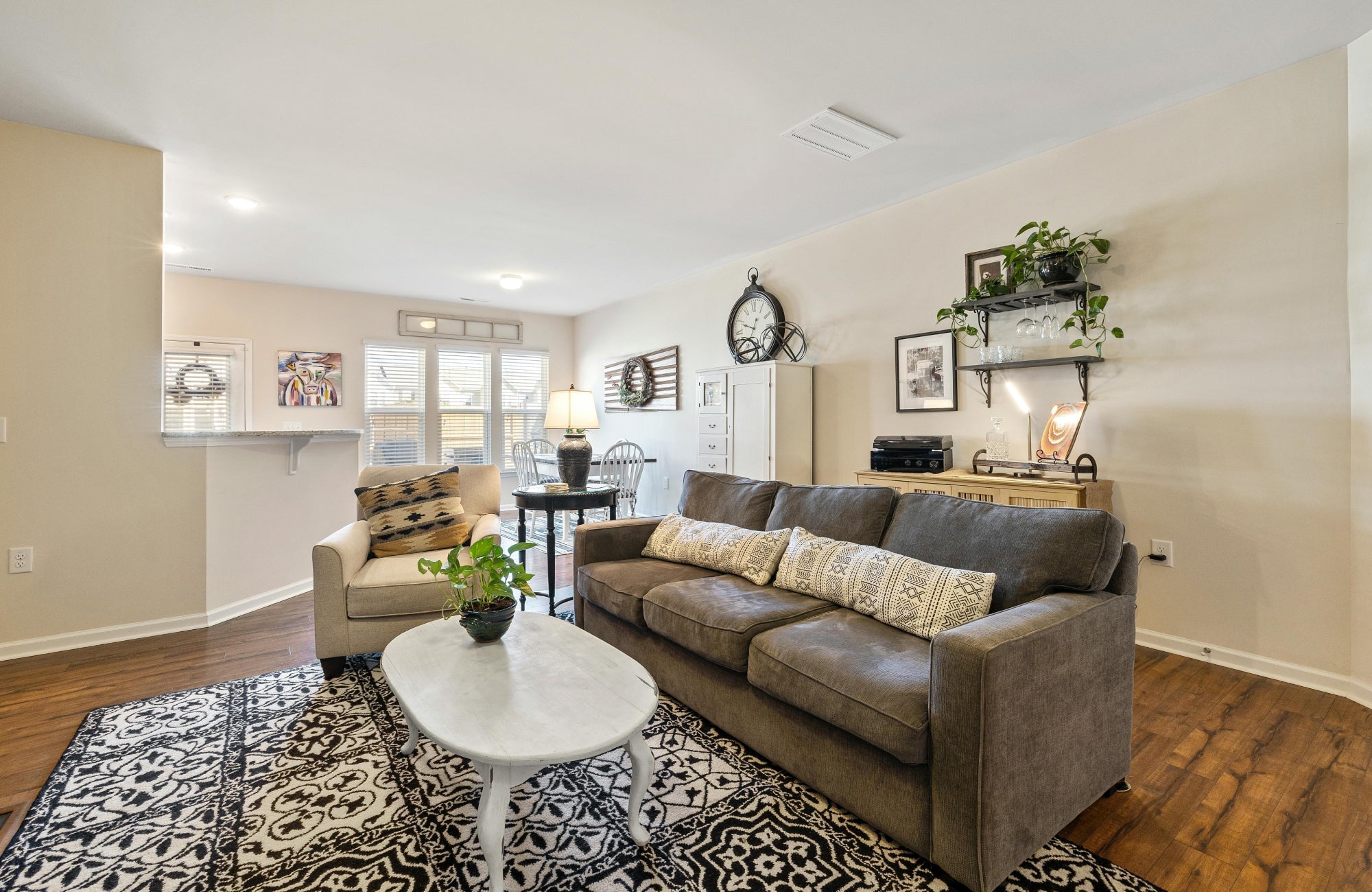 Black and white patterned rug with ornate motifs anchoring a cozy living room with neutral furniture and warm wood floors.