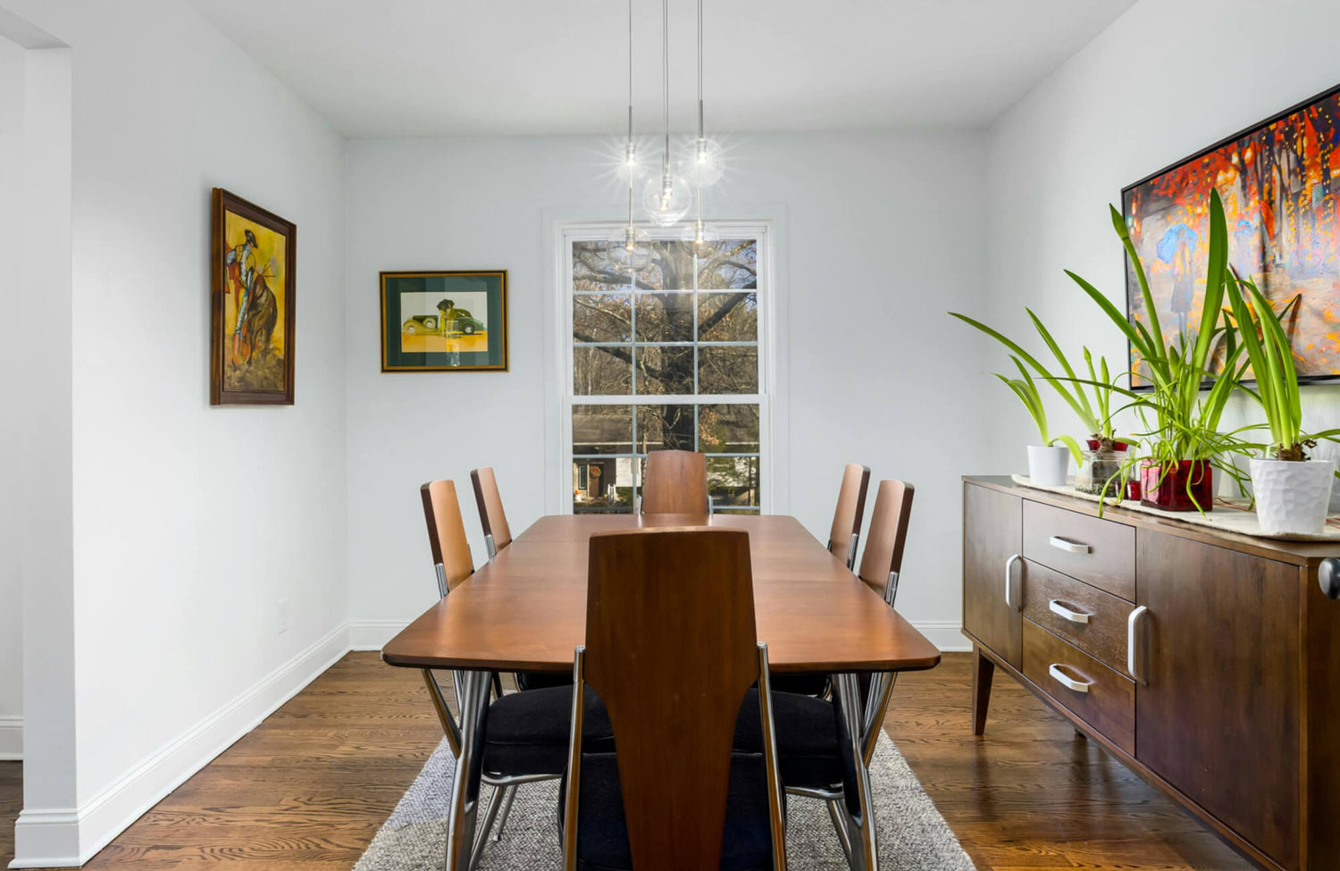 Contemporary dining room lighting showcases a cluster of clear glass globe pendant lights suspended above a warm wood dining table.