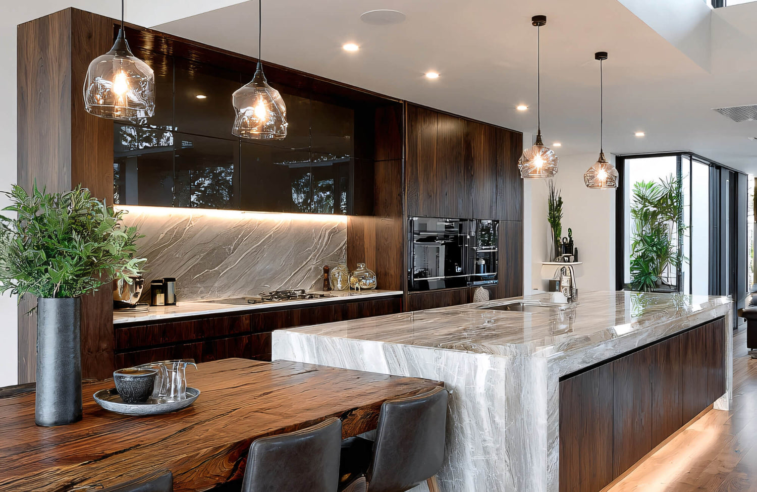 Modern kitchen island with warm wood cabinetry and glass pendant lights, blending antique-inspired lighting with contemporary finishes.