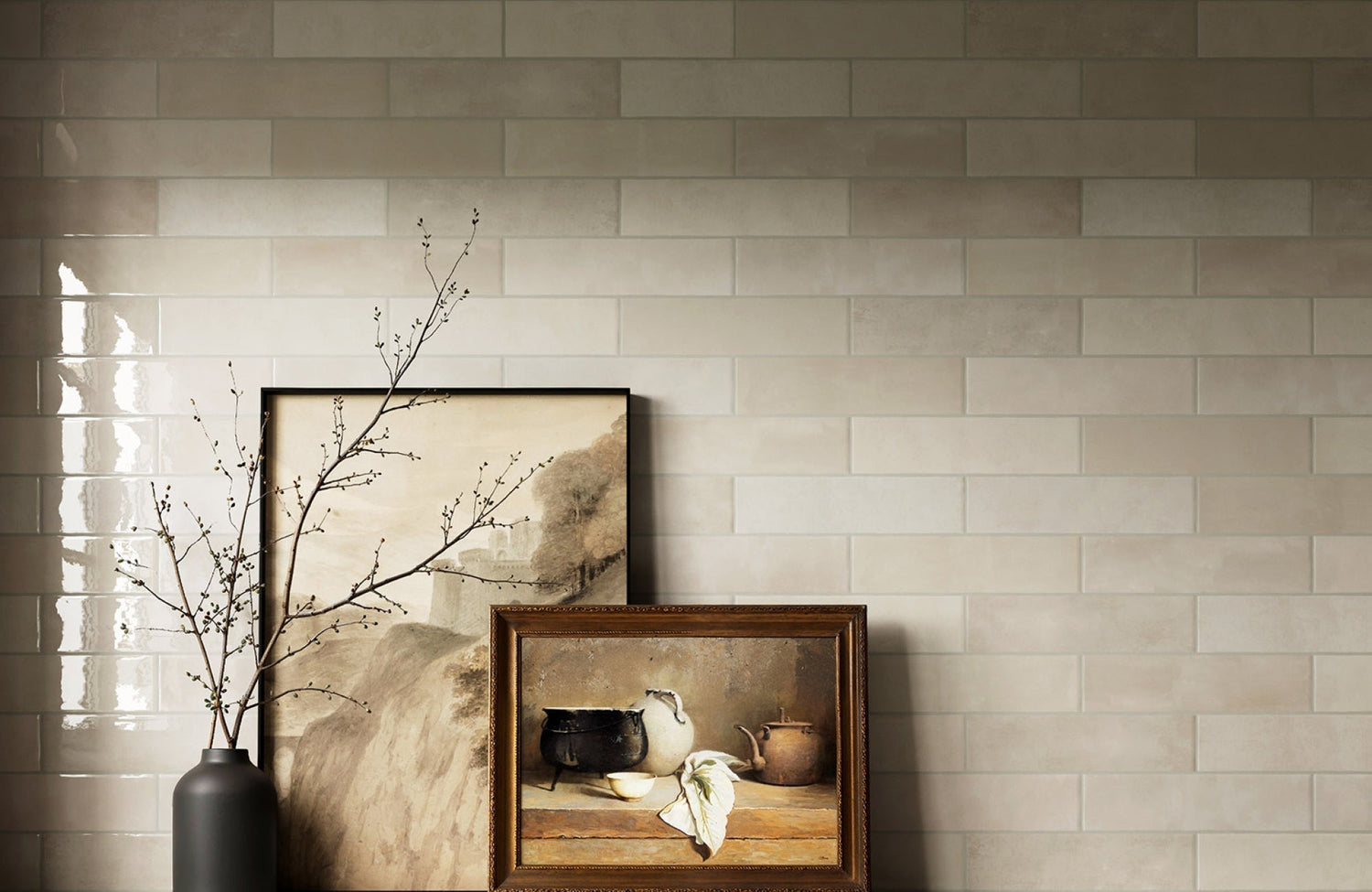 Beige ceramic subway tiles with soft neutral grout lines, styled with artwork and dried branches on display.