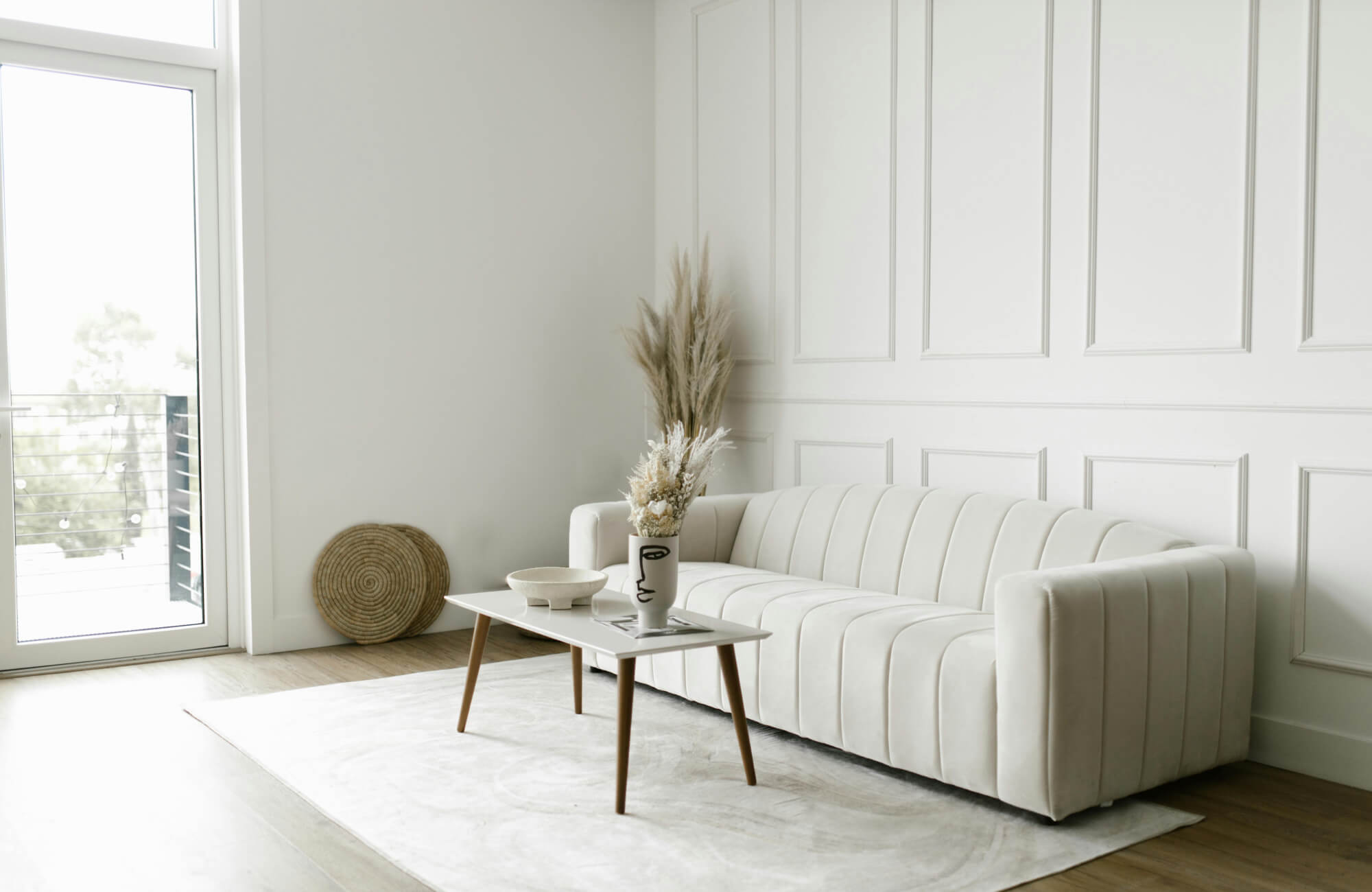 A bright living room with a soft white rug under a modern sofa and table, creating an airy, spacious feel in the space.
