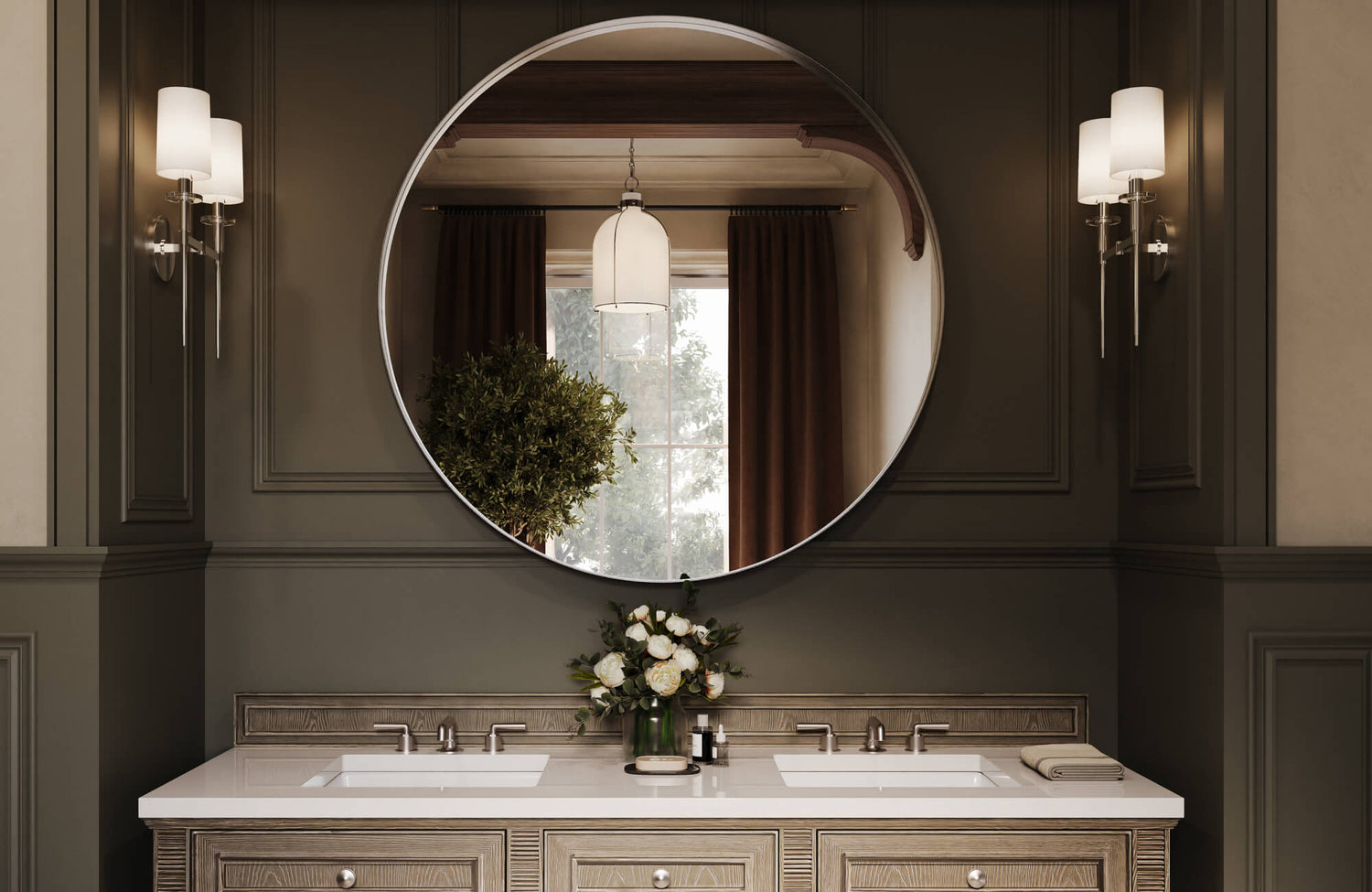 A classic bathroom setting showcasing a round mirror with double vanity, framed by elegant wall paneling, symmetrical sconces, refined wood cabinetry, and a crisp white countertop that together create a timeless and sophisticated ambiance.