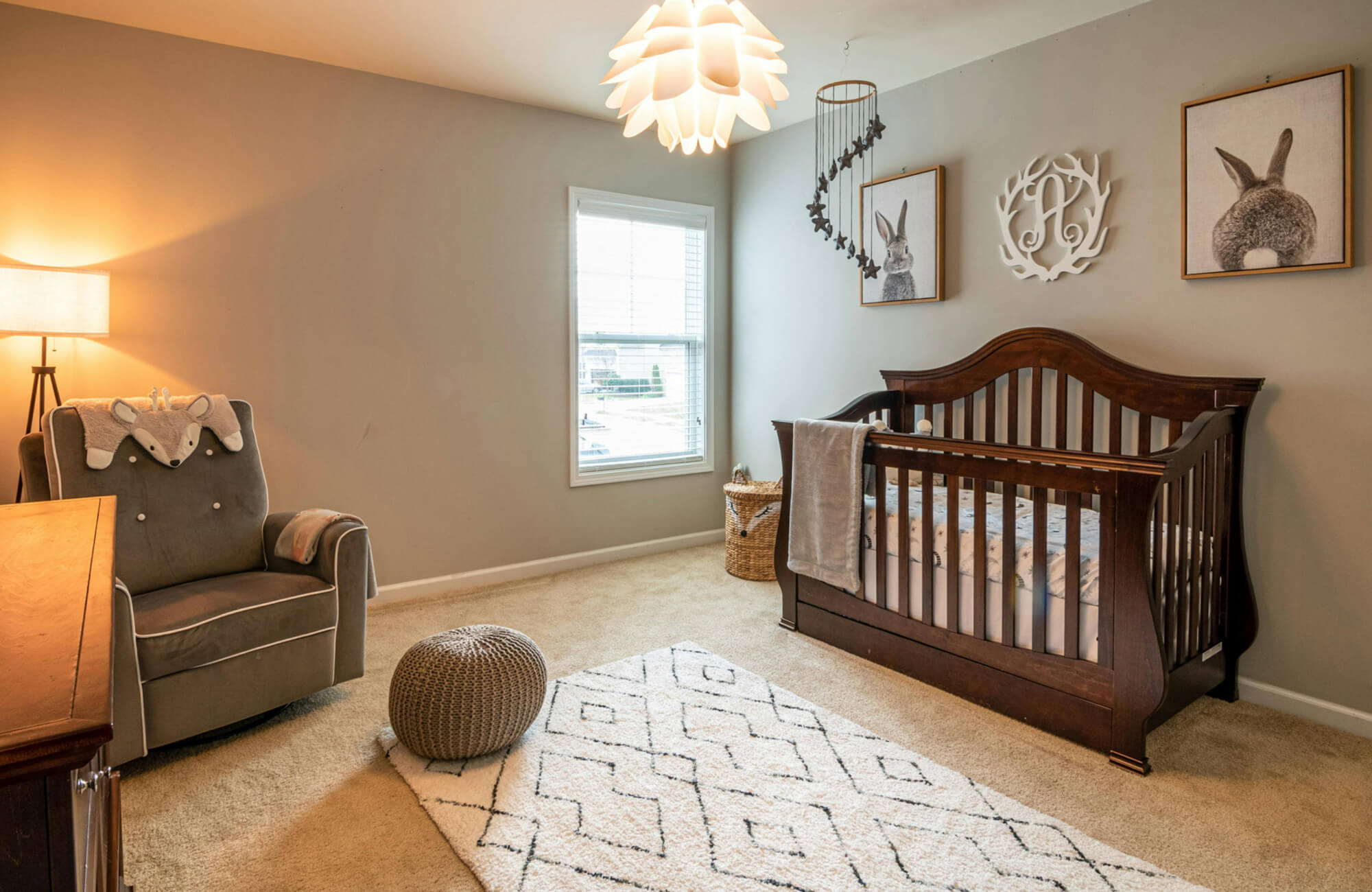 Soft patterned area rug centered beneath crib and seating, defining a cozy nursery floor zone with clear walkways around it.
