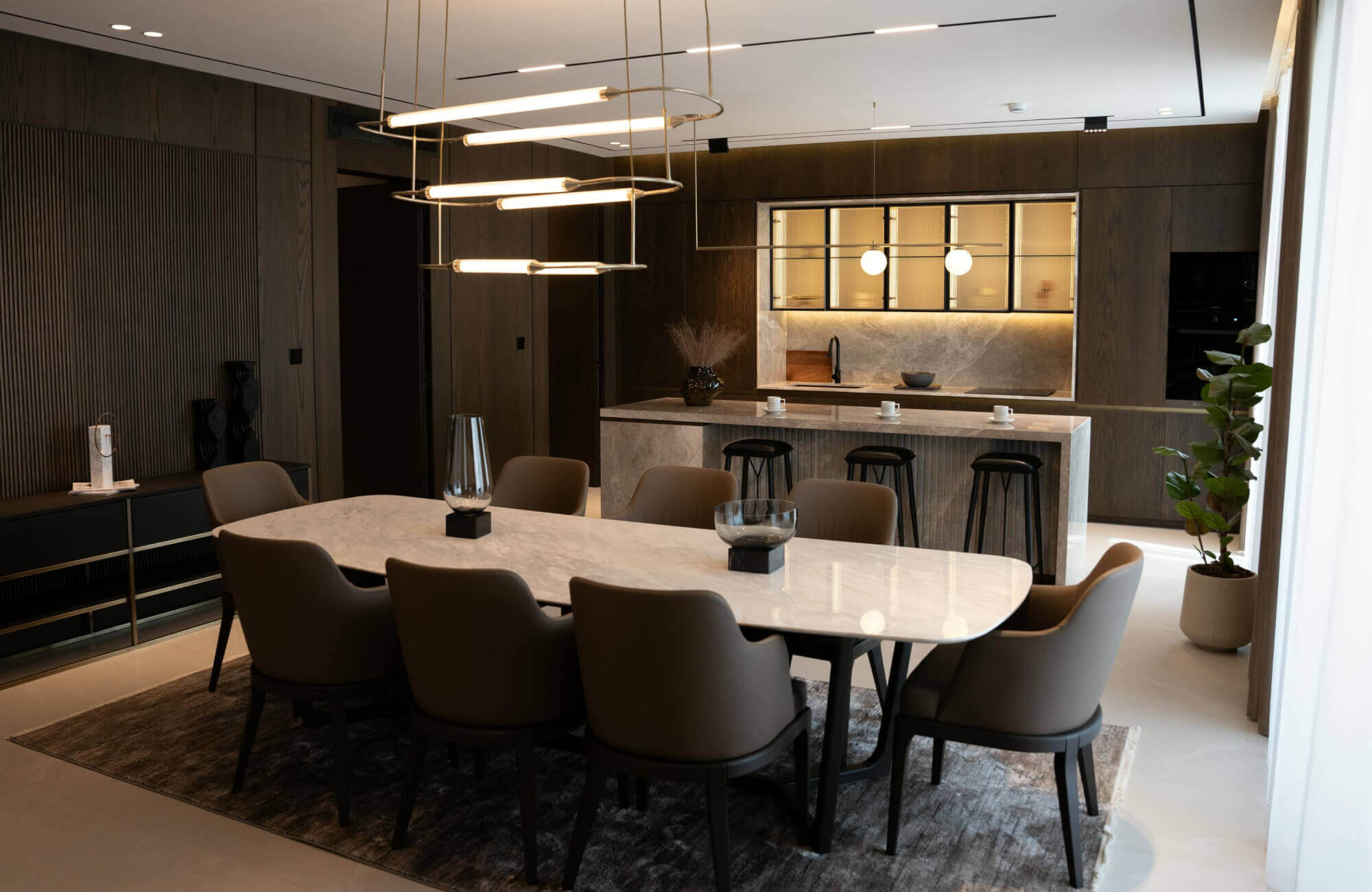 Modern dining room with a sleek rectangular marble-top table surrounded by upholstered chairs and pendant lighting.