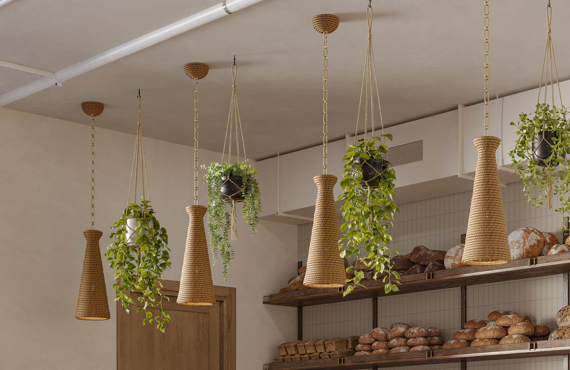 Bakery ceiling featuring woven rattan cone pendant lights with gold chains and hanging greenery for an earthy modern pendant light choice