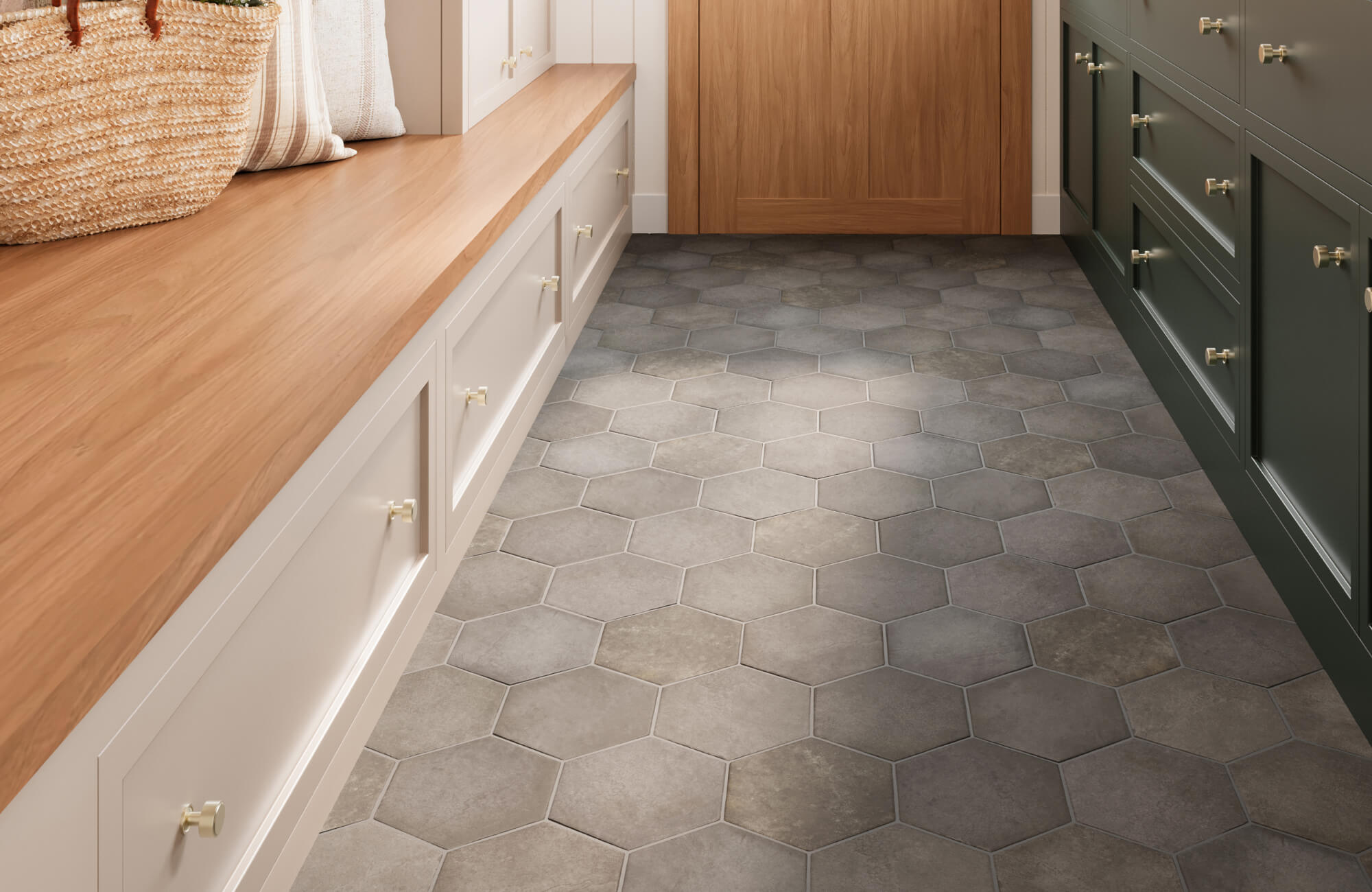 Bright mudroom with warm wood cabinetry and built-in seating, anchored by a gray hexagon tile floor that adds subtle texture and modern geometric interest to the inviting, functional space.