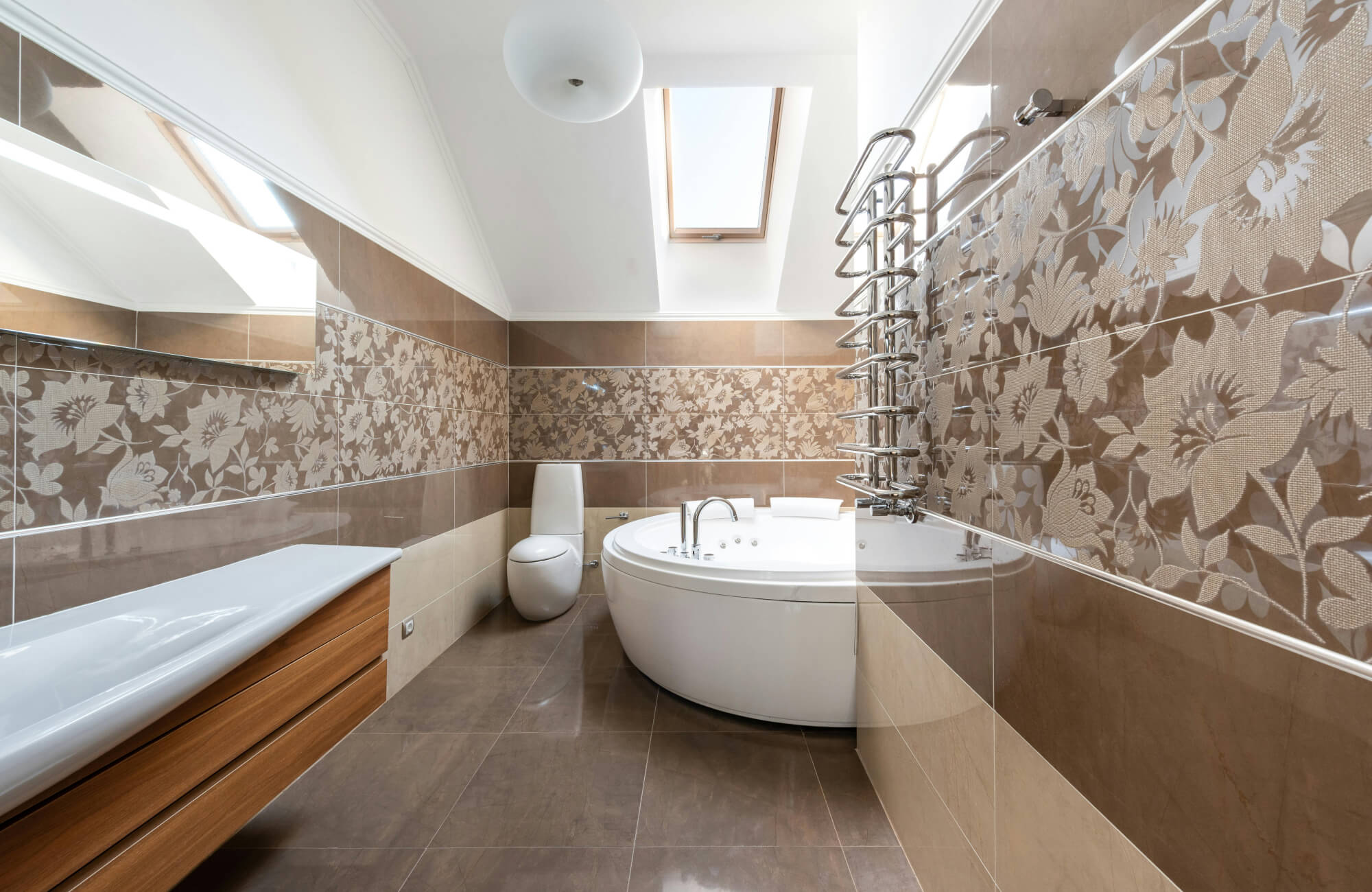 Elegant bathroom renovation showcasing a freestanding oval soaking tub, floral-patterned accent wall tiles in warm neutral tones, a skylight for natural light, and sleek modern fixtures that enhance the spa-like atmosphere.