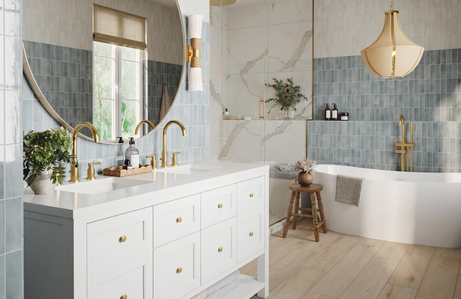 Bright bathroom featuring elegant vertical blue wall tiles, a large round mirror flanked by modern gold-and-white sconces, a white double vanity with brushed gold fixtures, and a sculptural pendant light above a freestanding tub.