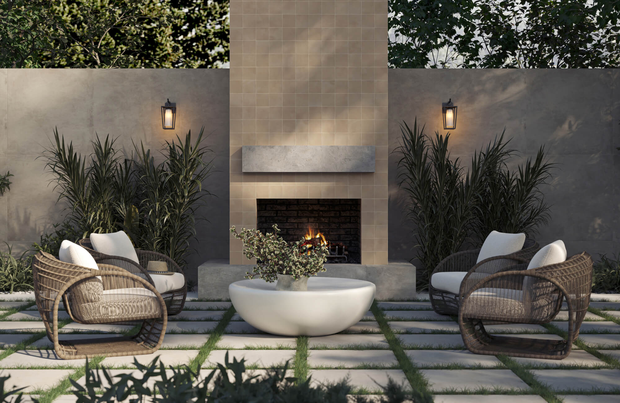 Elegant outdoor patio with woven lounge chairs, round coffee table, and built-in fireplace framed by lush greenery and warm lighting.