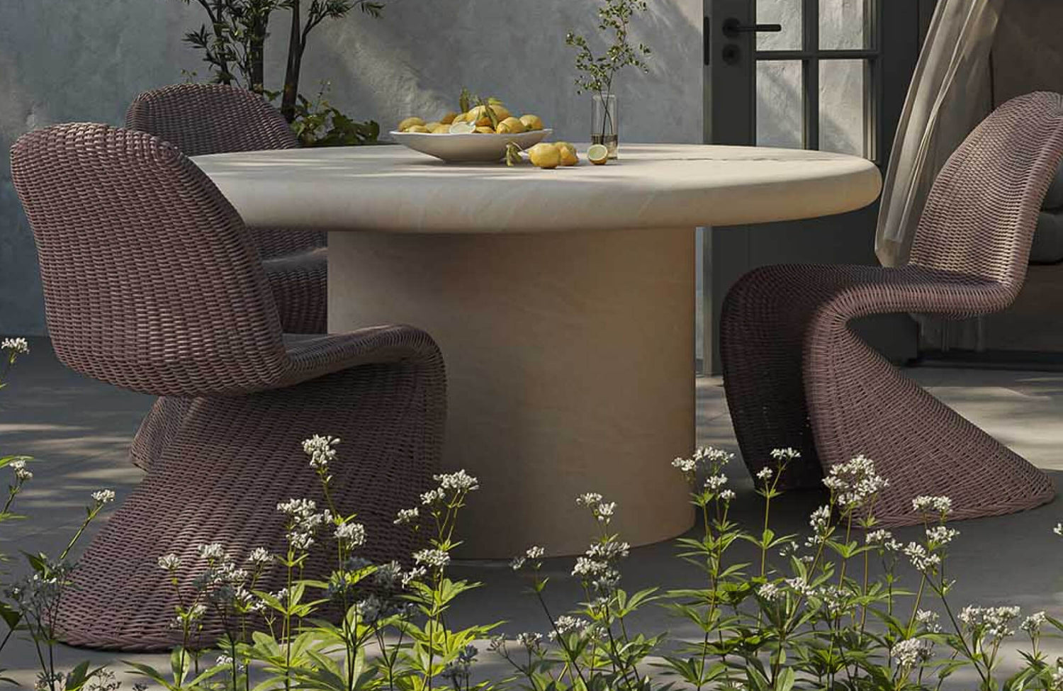 Outdoor dining chair with sculptural curved silhouette and woven texture, paired with a round table in a modern patio dining set surrounded by greenery.