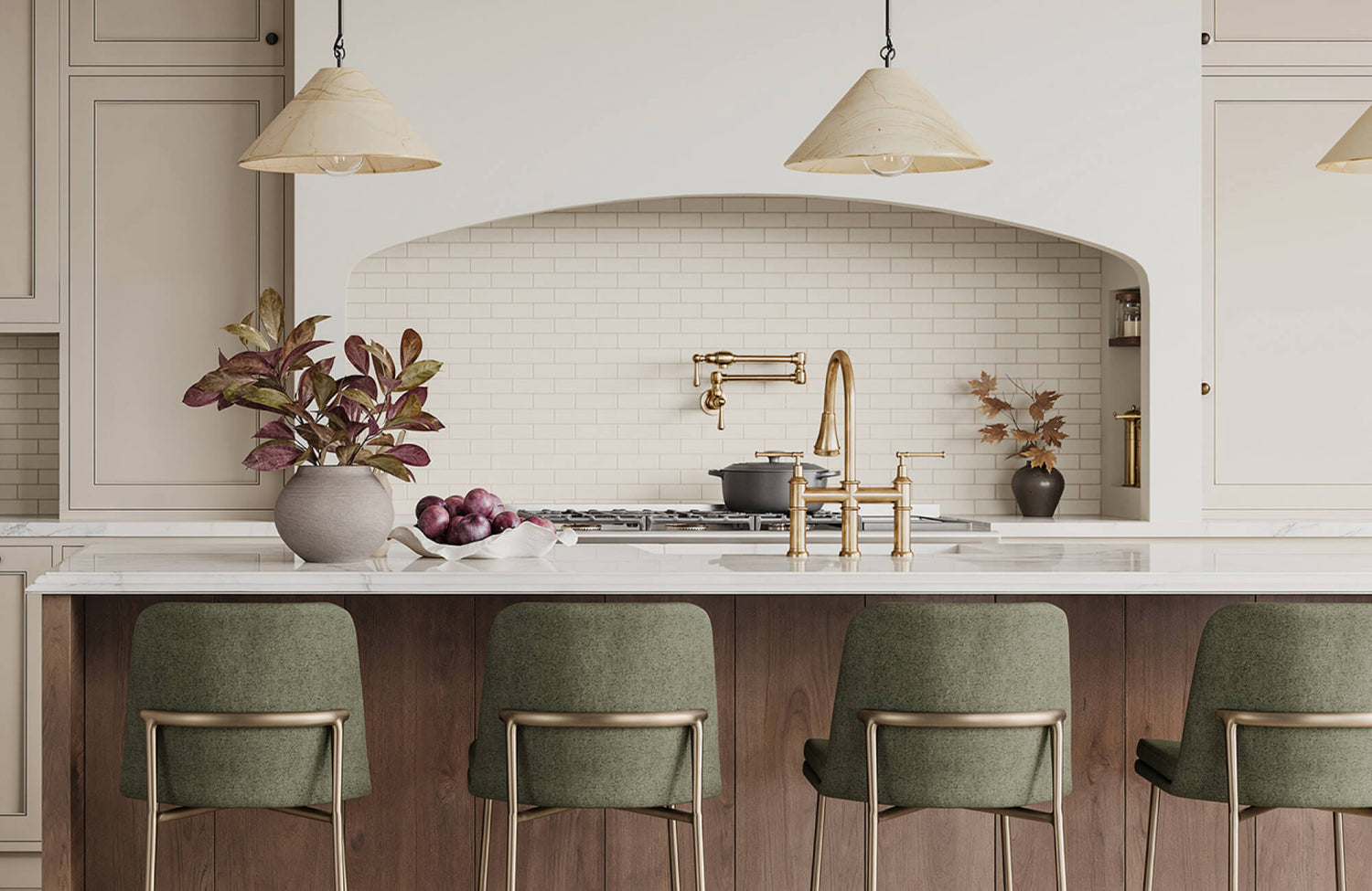 Warm-toned kitchen with brass fixtures, olive green bar stools, and a marble island set against a white subway tile backsplash.