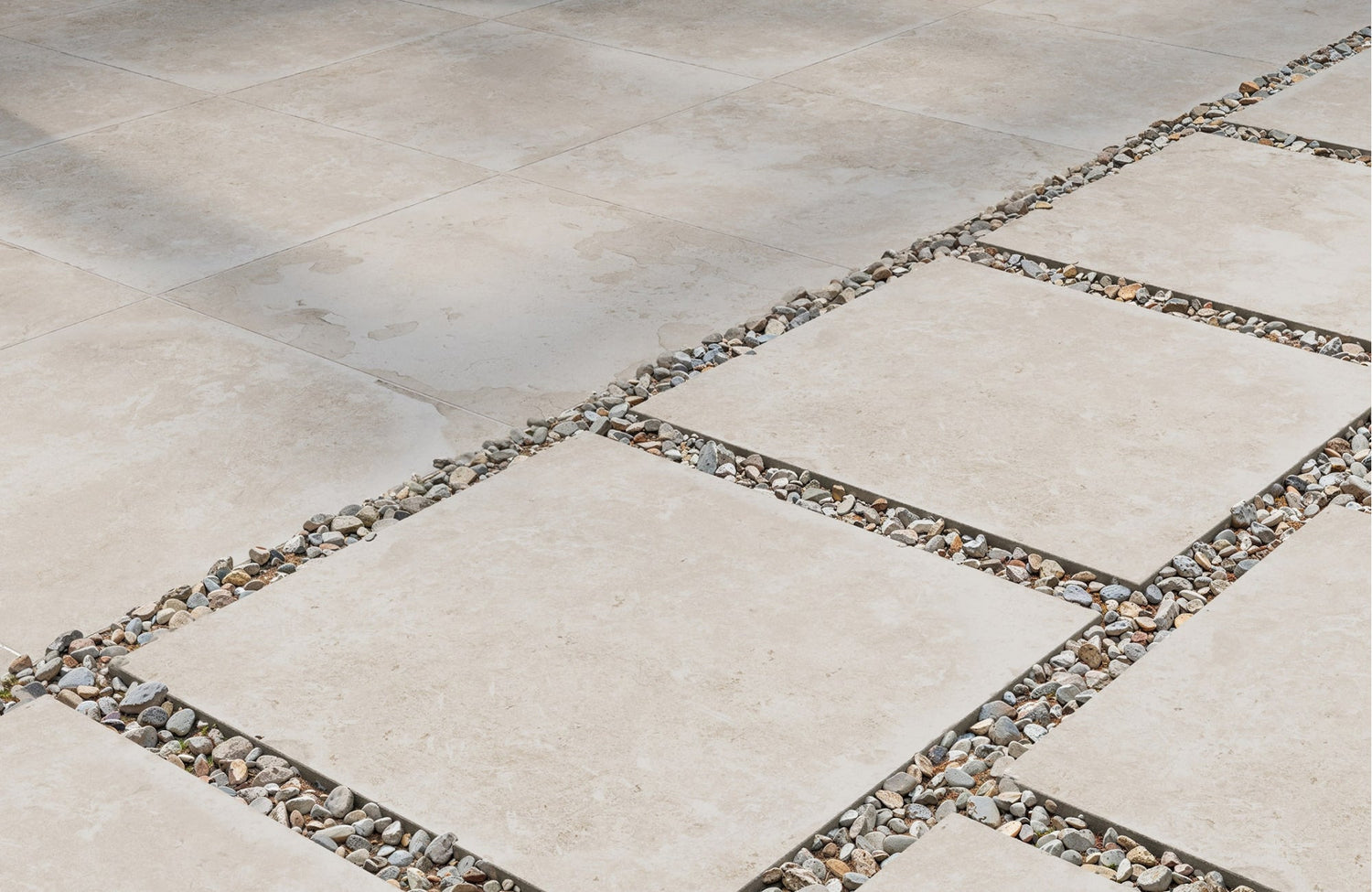 Close-up of beige porcelain pavers installed with decorative gravel joints, creating a clean and modern outdoor surface.