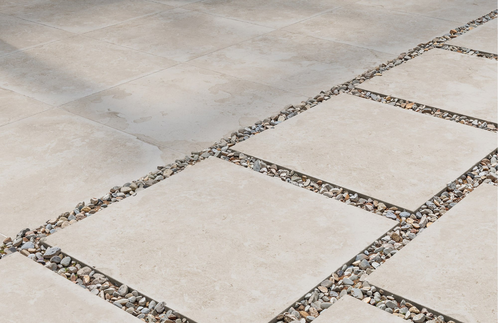 Close-up of beige porcelain pavers installed with decorative gravel joints, creating a clean and modern outdoor surface.