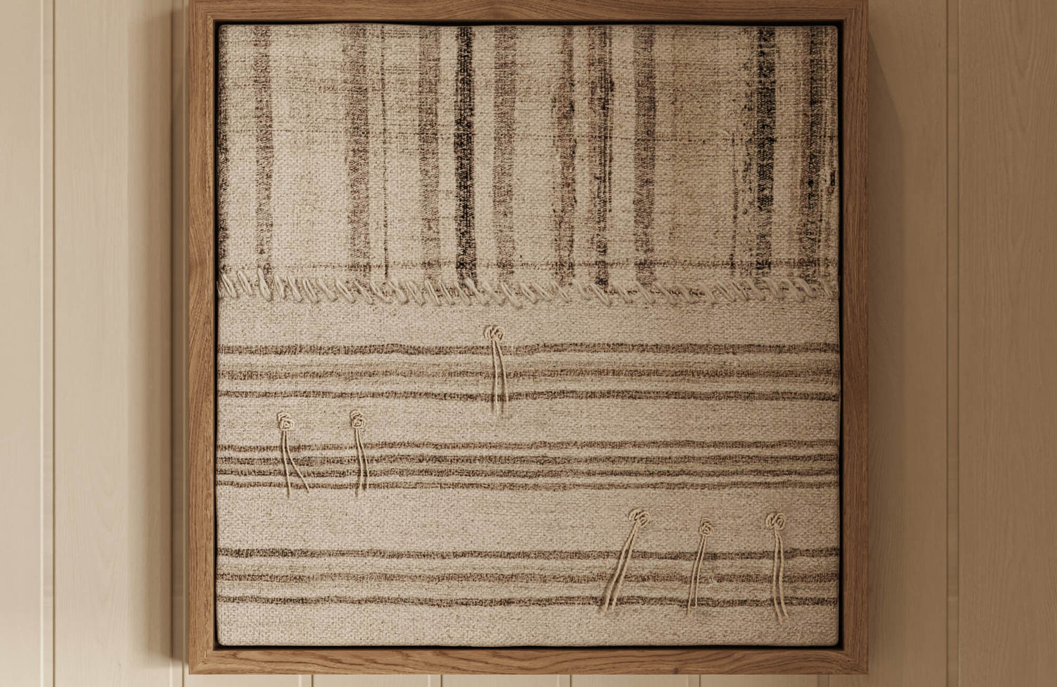 Beige and brown textile wall art framed in wood, showing a simple striped design that adds depth without overpowering the space.