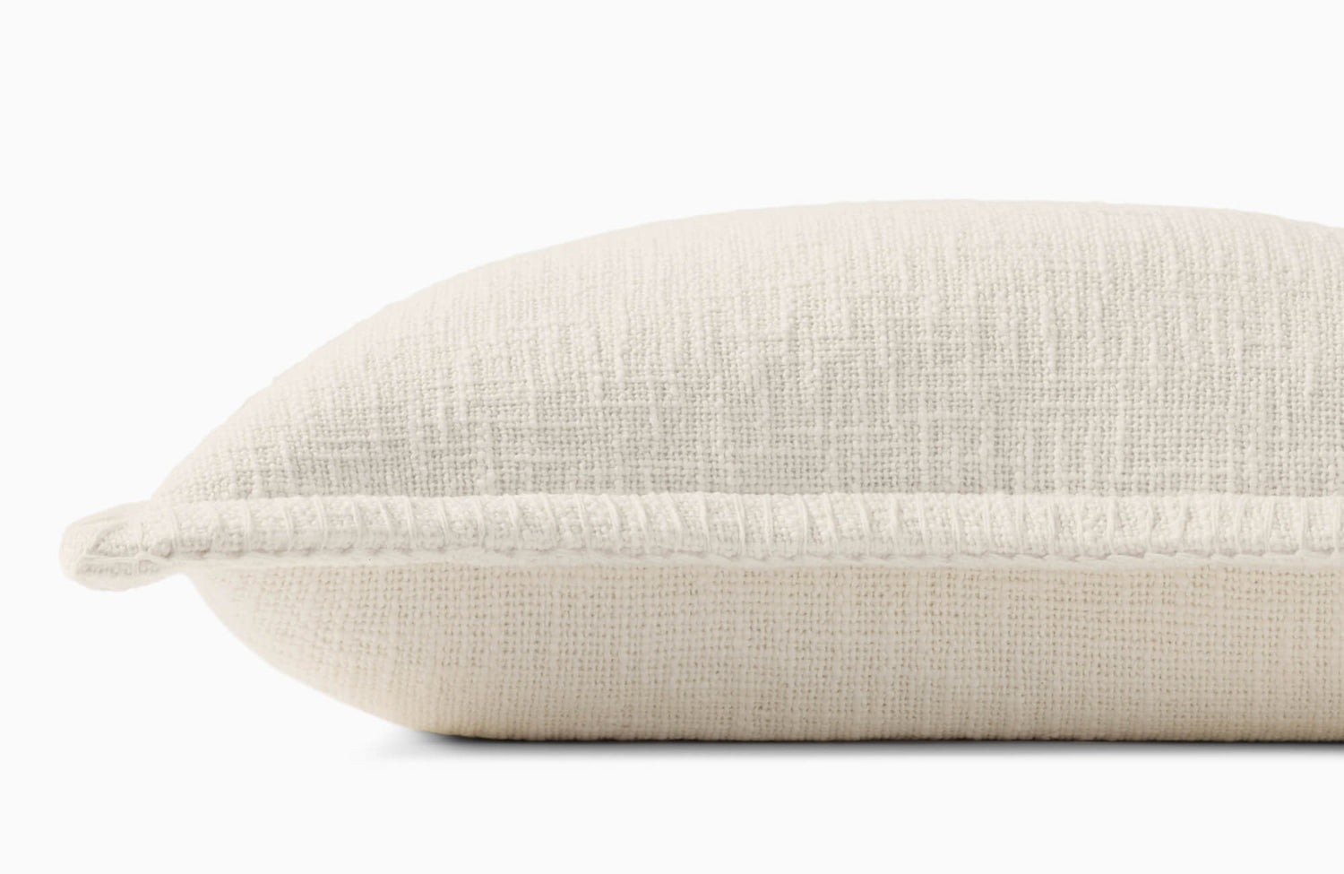 Close-up side view of a decorative throw pillow cover with a textured white weave, rounded profile, and raised trim accent along the seam.