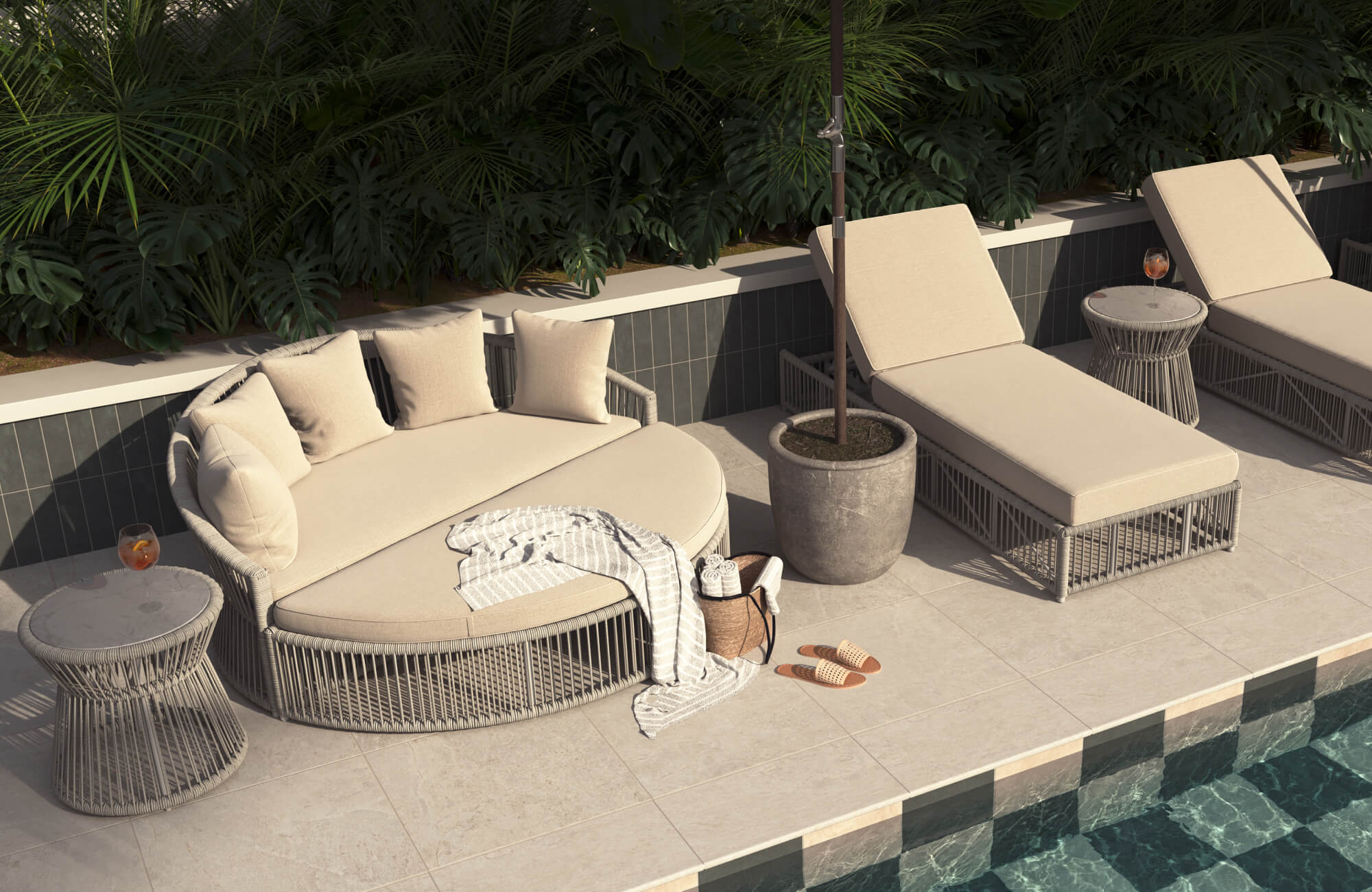 Curved outdoor daybed with beige cushions, woven side tables, and matching chaise lounges arranged beside a tiled pool and dense tropical greenery.