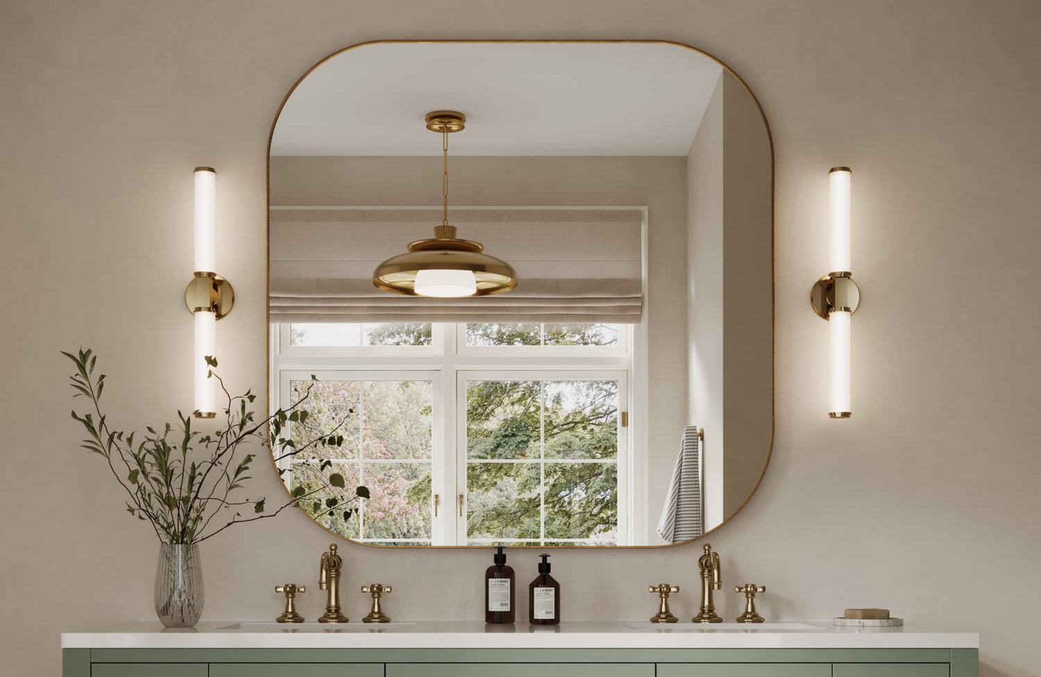 Elegant sink area featuring a wide, rounded mirror, gold fixtures, and minimalist sconces with a backdrop of greenery outside the window.
