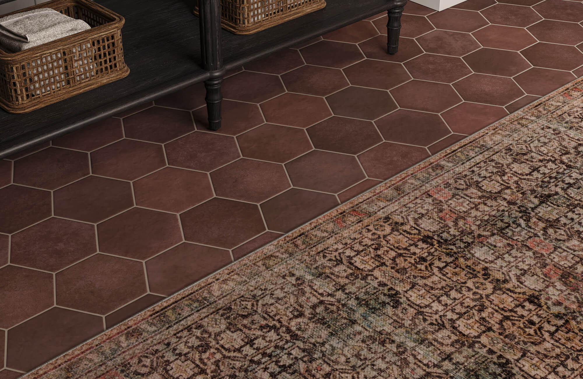 Warm brown hexagon floor tiles paired with a vintage-style rug, creating a rich, textured flooring layer under a black bench with woven baskets.