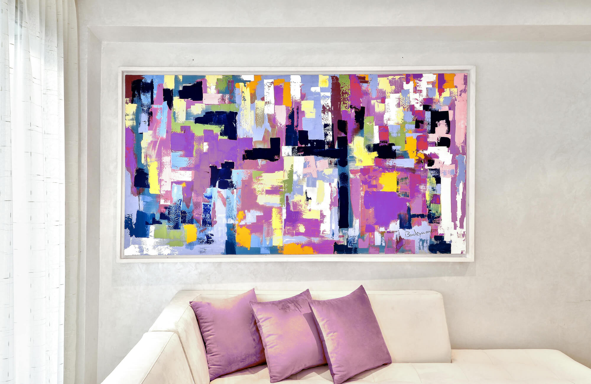 Canvas painting wall art with vibrant abstract geometric blocks in purple, yellow, and blue above a modern white sofa.