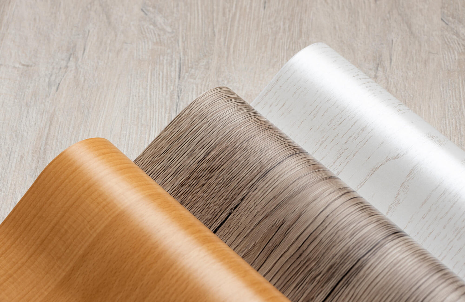 Rolled vinyl plank samples in warm and cool wood finishes, highlighting the realistic texture and color range of luxury vinyl flooring.