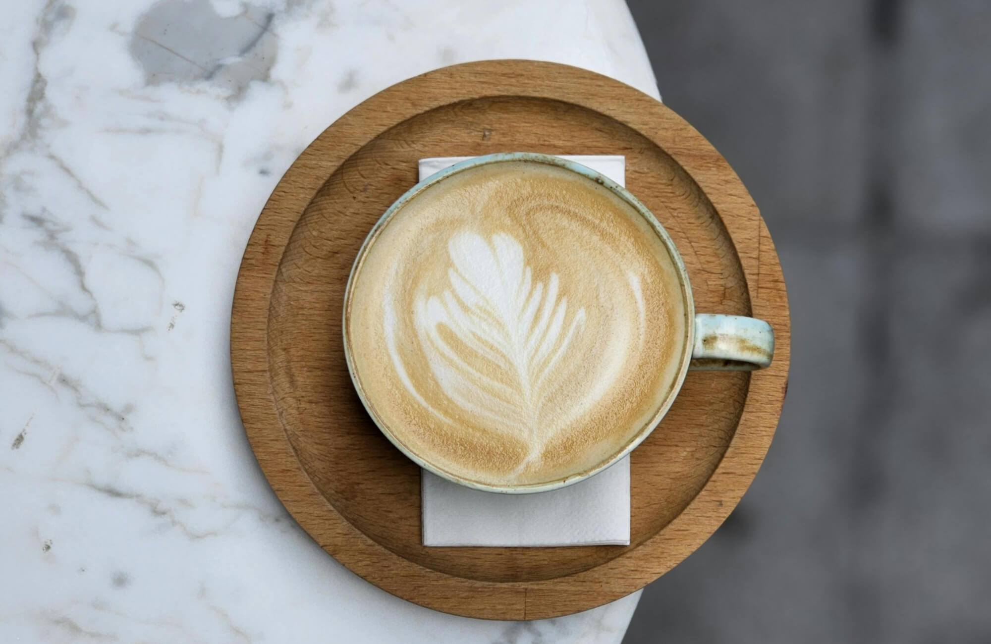 Coffee cup on a marble tabletop with a coaster, illustrating how barriers help prevent moisture rings and stains on marble surfaces.