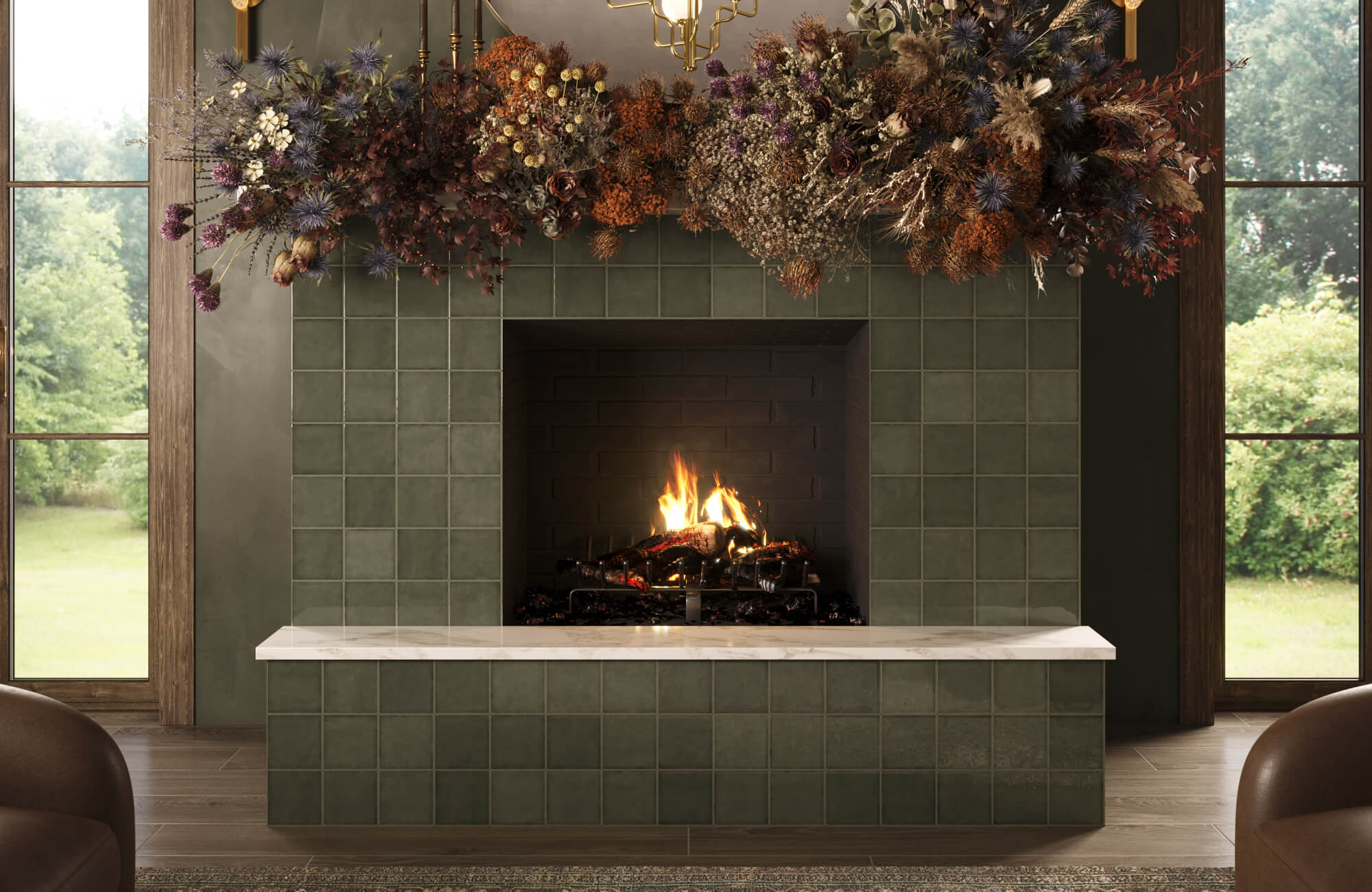 A modern tiled fireplace in deep olive green with a marble hearth, framed by large windows and topped with an abundant dried floral arrangement.