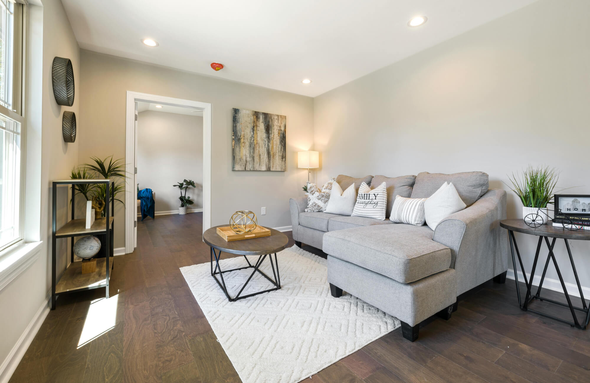 A White rug with a gray sectional sofa and wooden table adds texture and balance to a cozy, neutral living room setup.