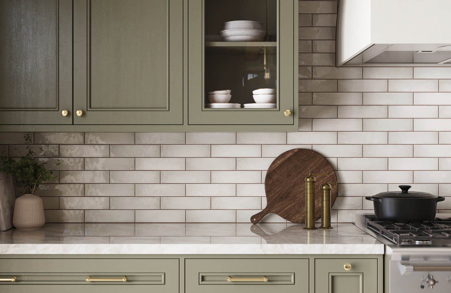 White subway tile backsplash paired with sage green cabinetry, marble countertops, and brass accents for a warm, timeless kitchen design.