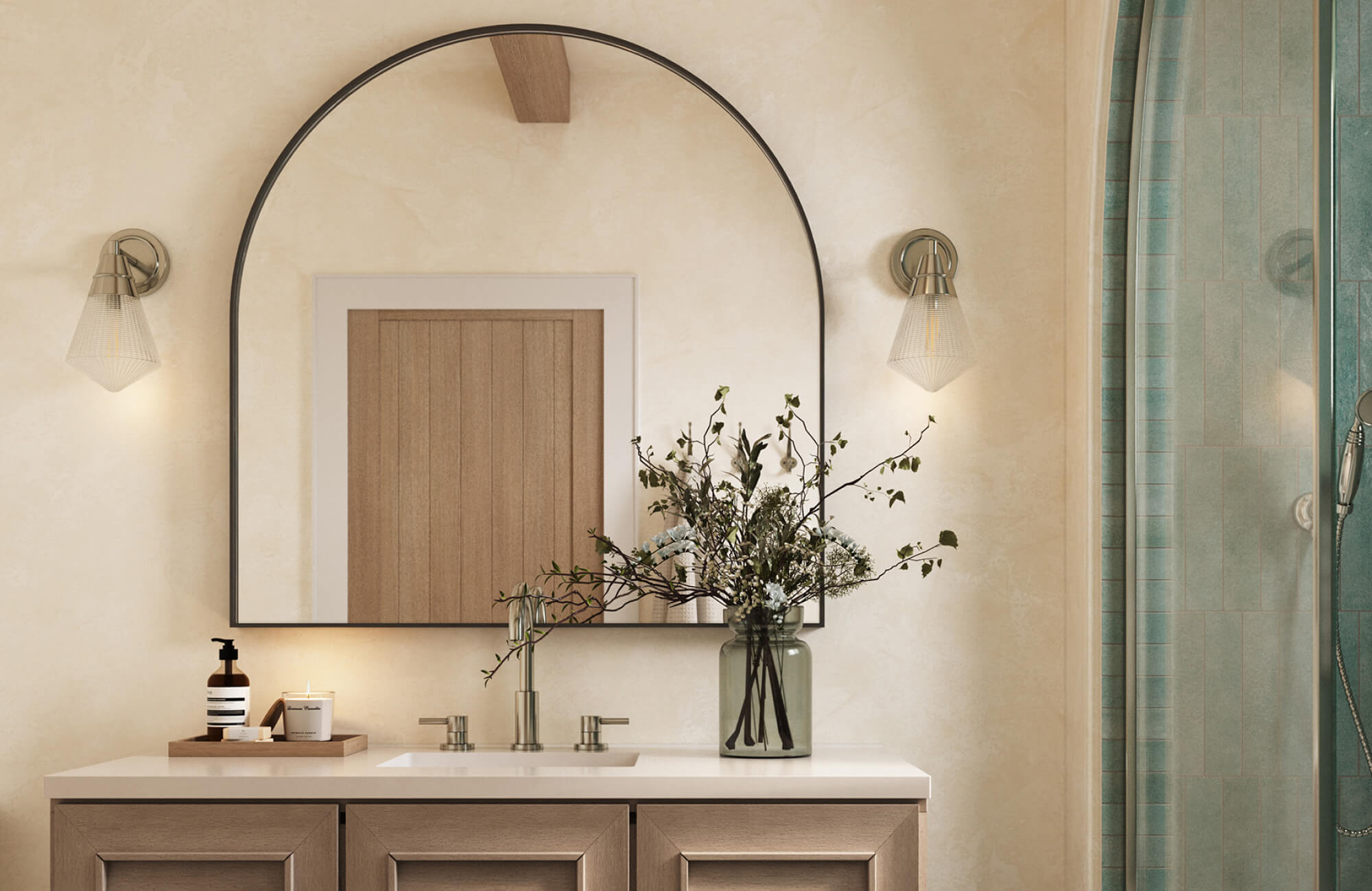 Bathroom vanity styled with an arch mirror centered above the sink, softly framed by wall sconces and warm neutral finishes.