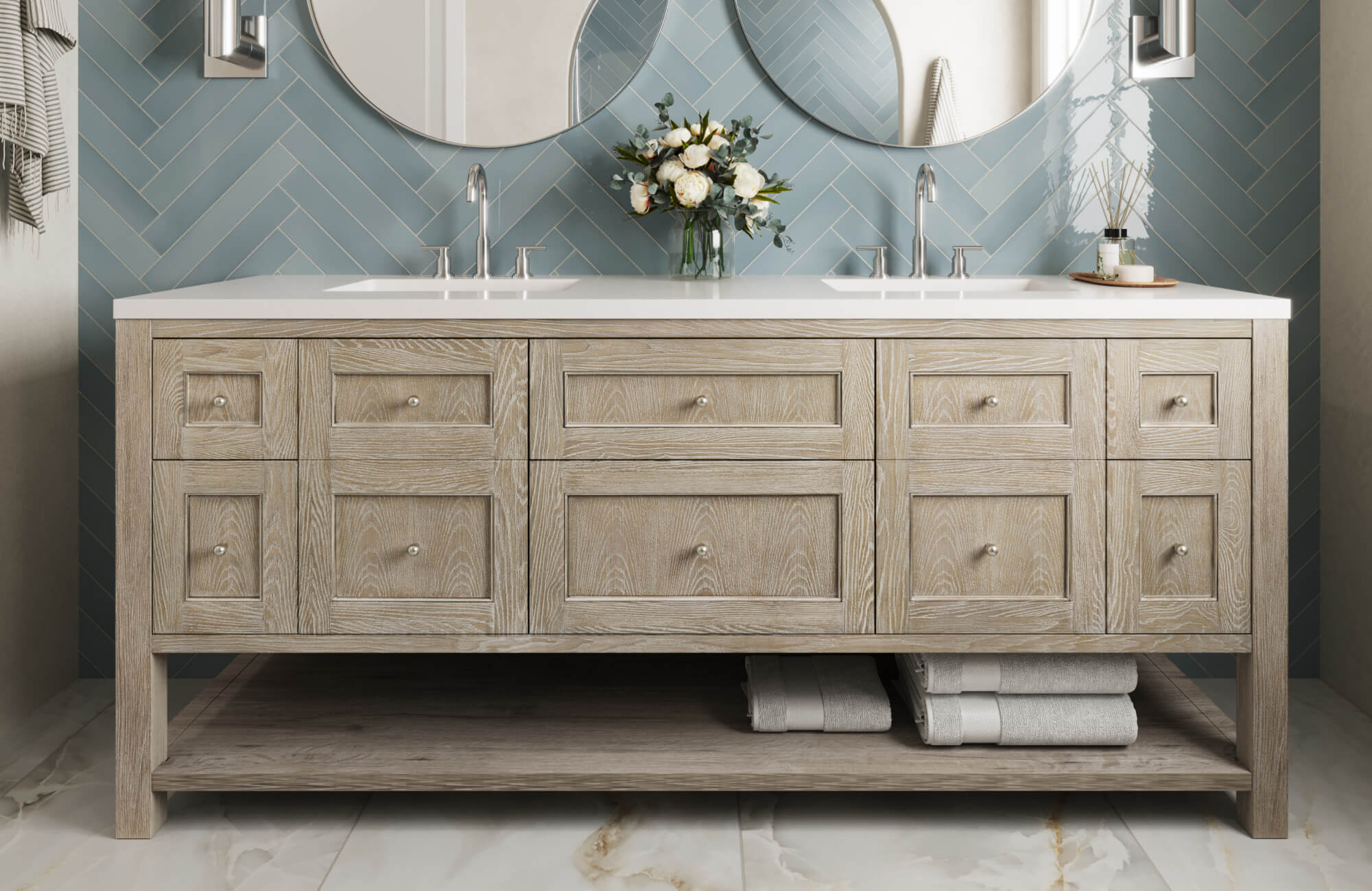 Light wood vanity with double sinks pairs beautifully with blue herringbone wall tiles and marble look flooring for a fresh spa vibe.