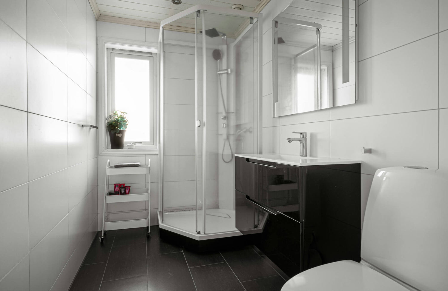 Sleek white rectangular tiles contrast with dark flooring in this minimalist bathroom featuring a glass-corner shower and modern floating vanity.