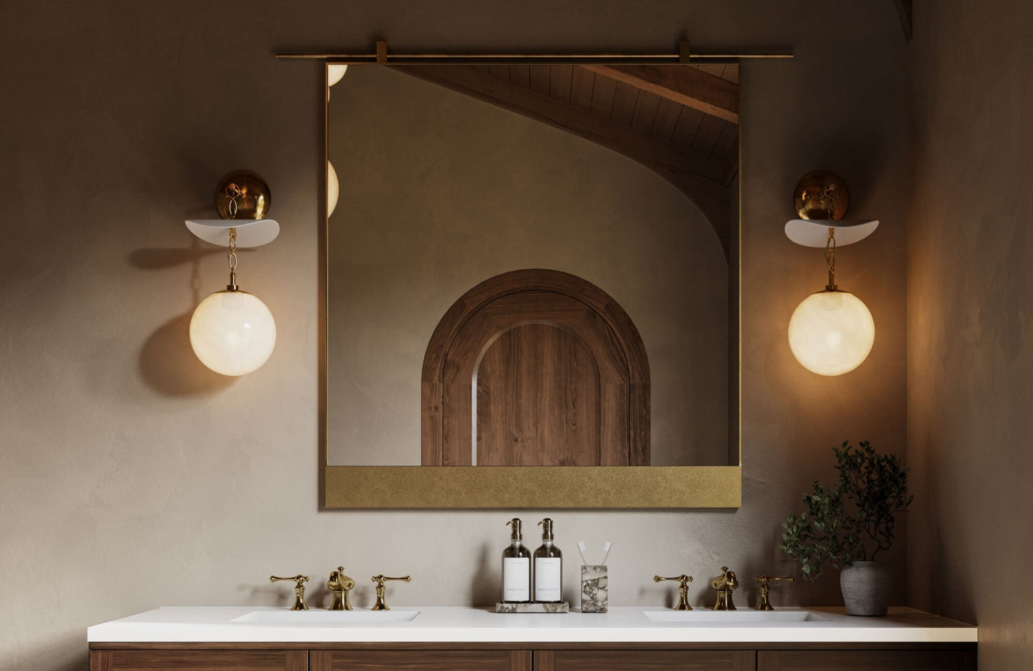 Elegant bathroom vanity with brass fixtures, globe sconces, and a large gold-framed mirror reflecting an arched wood door.