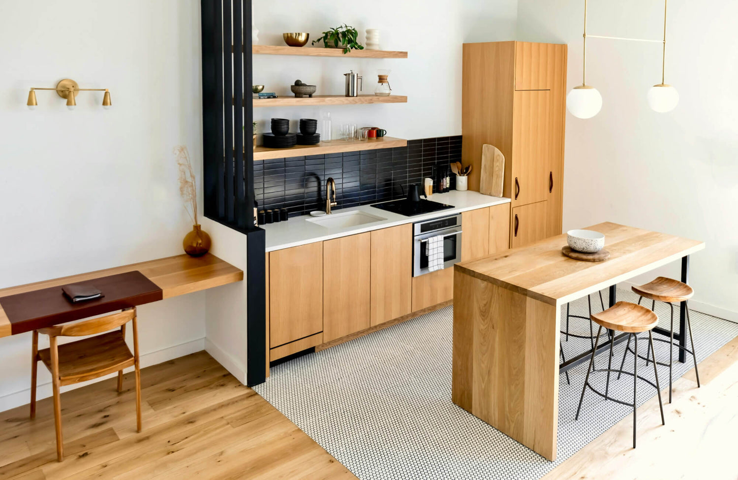 Modern kitchen with light wood cabinets, black tile backsplash, and a wood island set against a bright, open-concept layout.