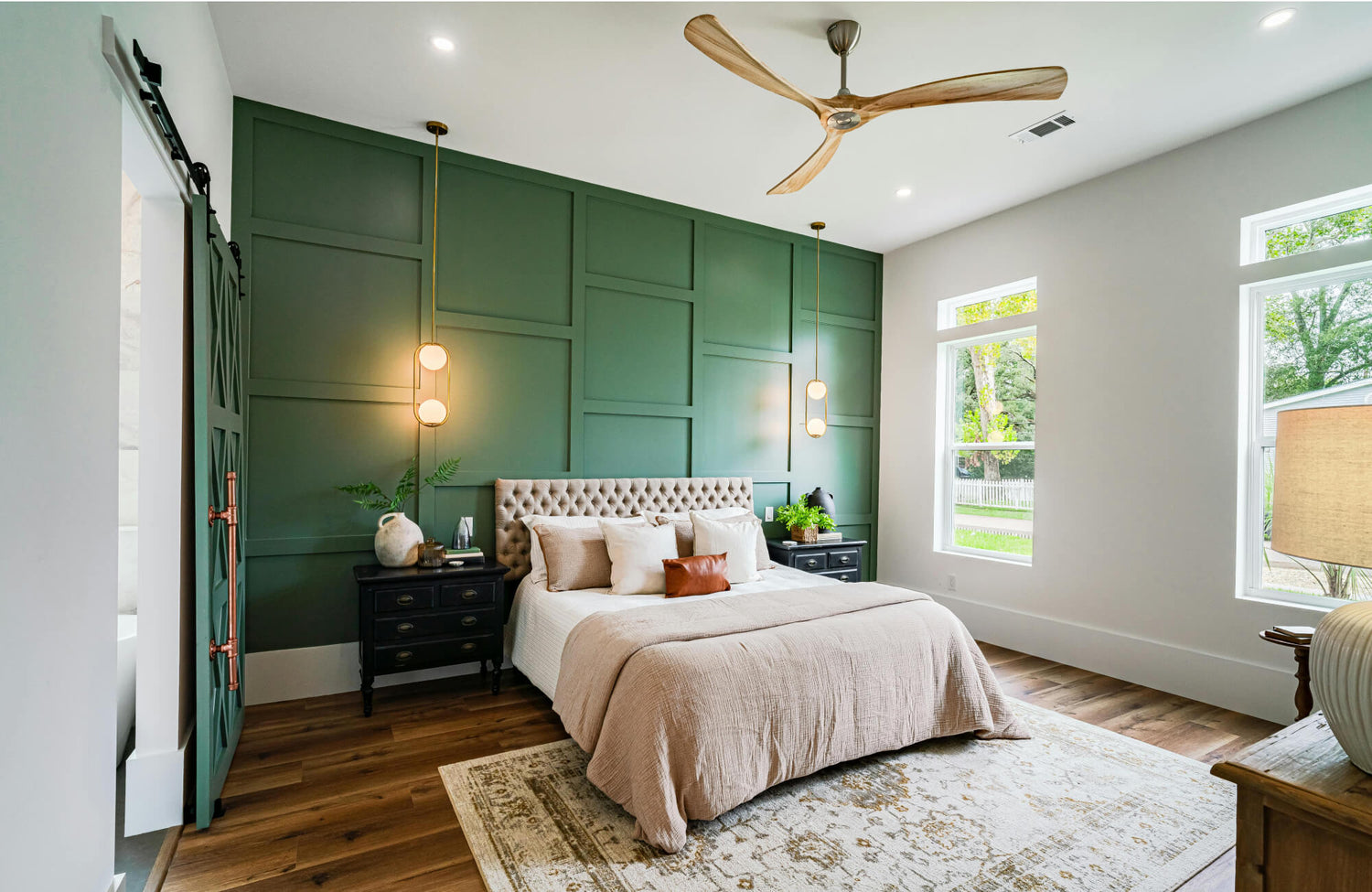 Bedroom with a light beige rug enhancing warmth against a green accent wall and wood flooring.